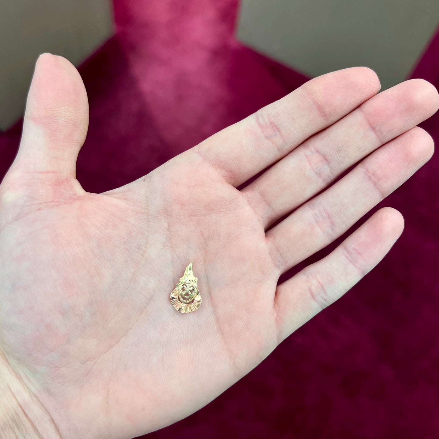 A small gold clown pendant charm. The clown's face and hat are yellow gold, and his neck frills are rose gold.