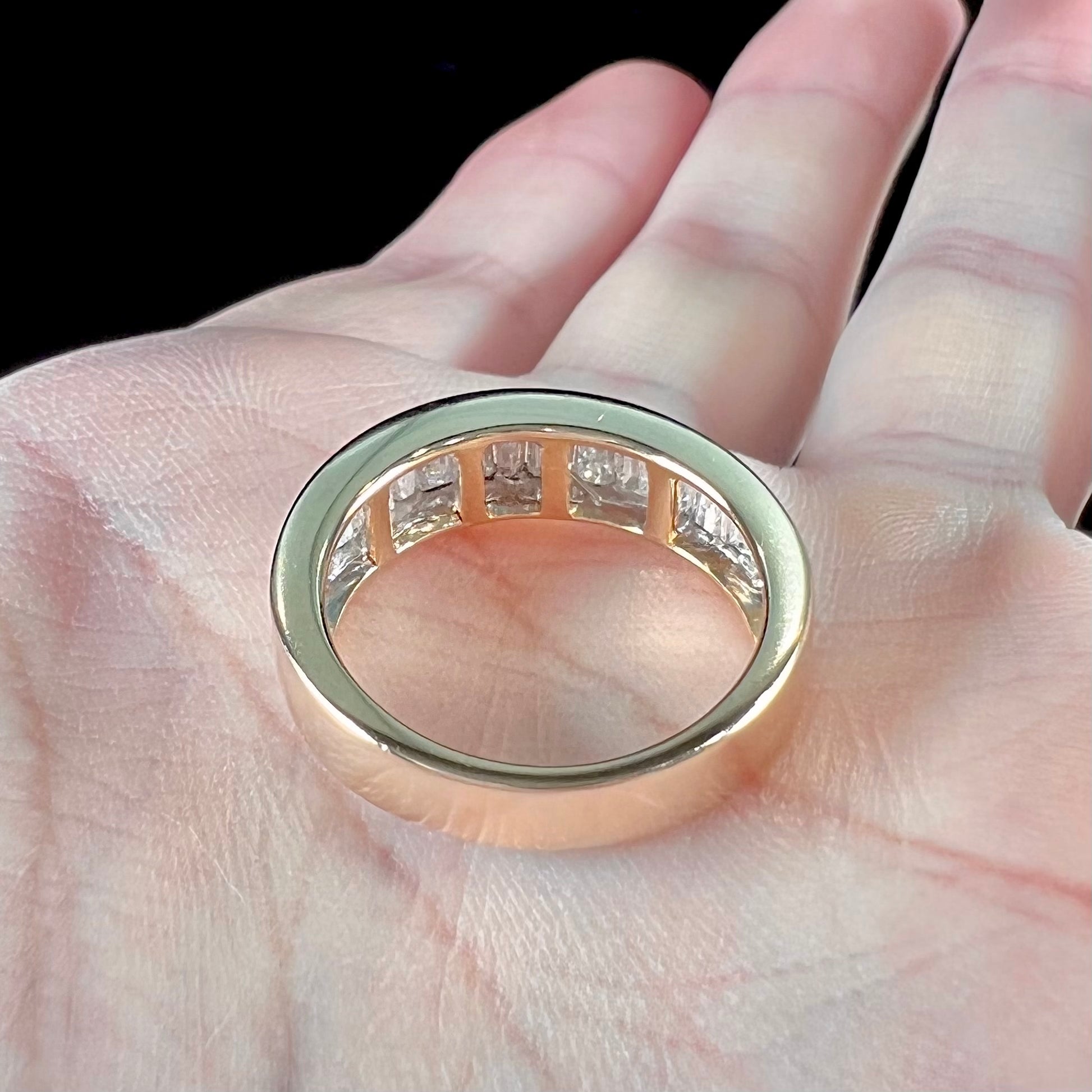 A ladies' yellow gold ring channel set with a row of baguette cut diamonds.
