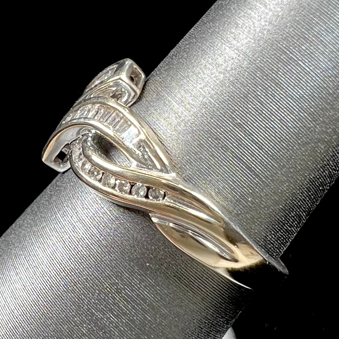 A ladies' white gold crisscross style ring channel set with round and baguette cut diamonds.