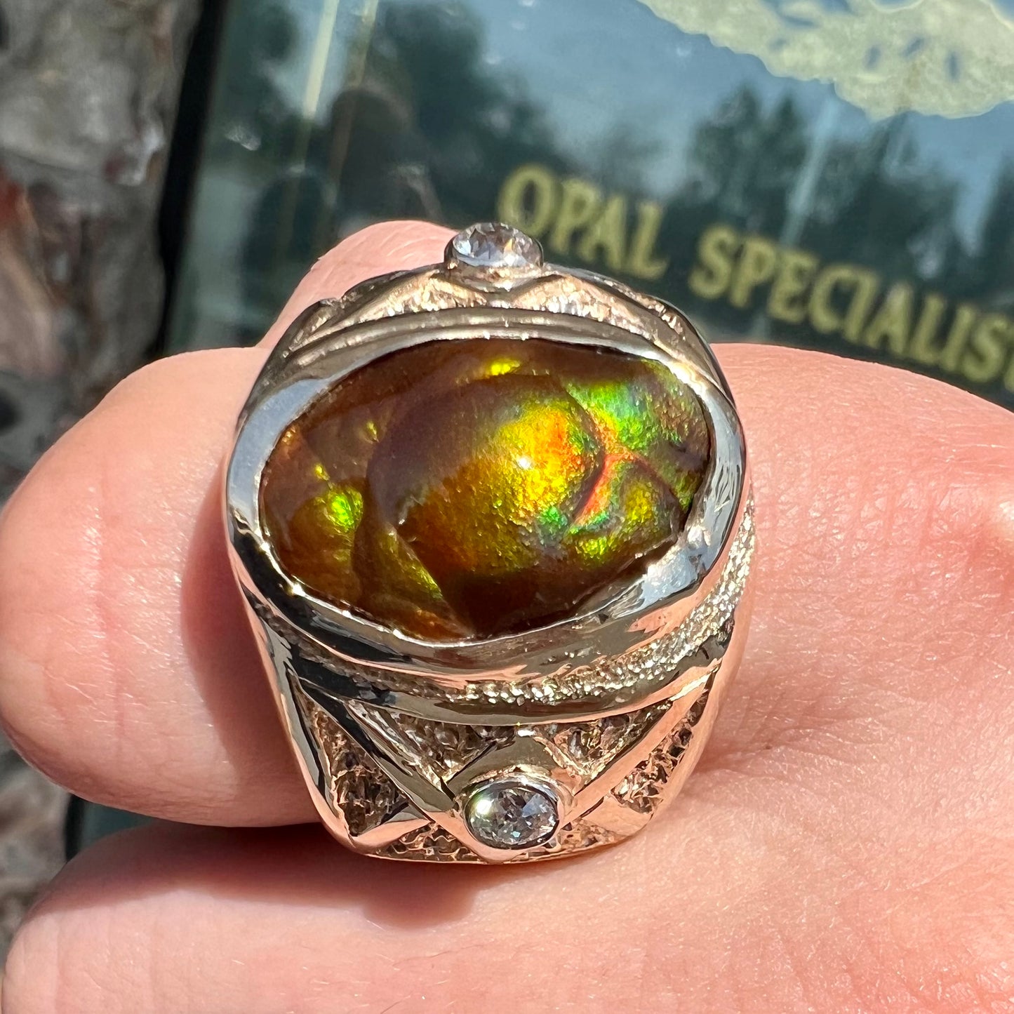 A men's solid yellow gold fire agate and diamond ring. The fire agate displays predominantly red and green.