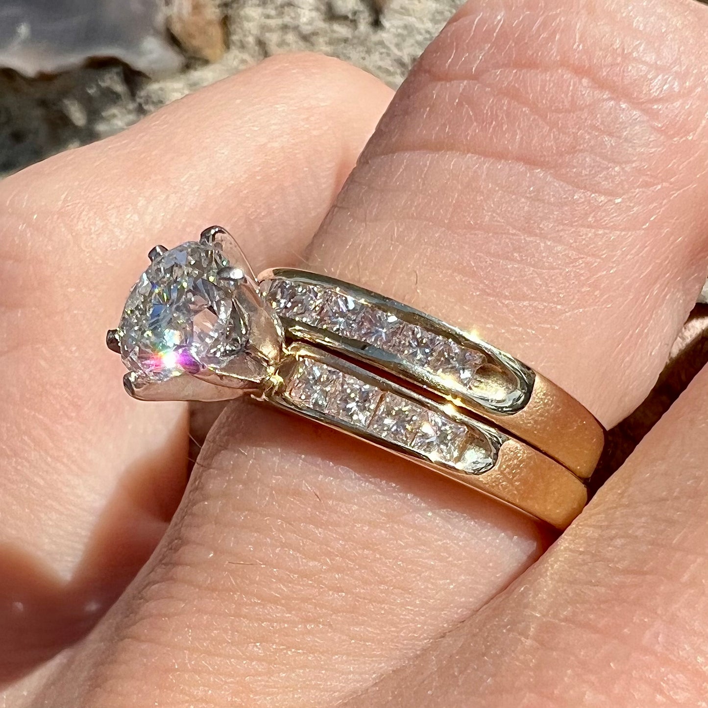 A diamond engagement and wedding ring set. The center stone is a 1 carat round diamond, and the side stones are channel set princess cut diamonds.