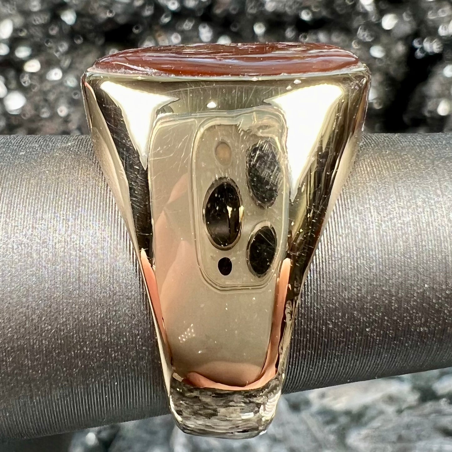 A yellow gold solitaire fire agate men's ring. The fire agate is oval shape, and red and green in color.