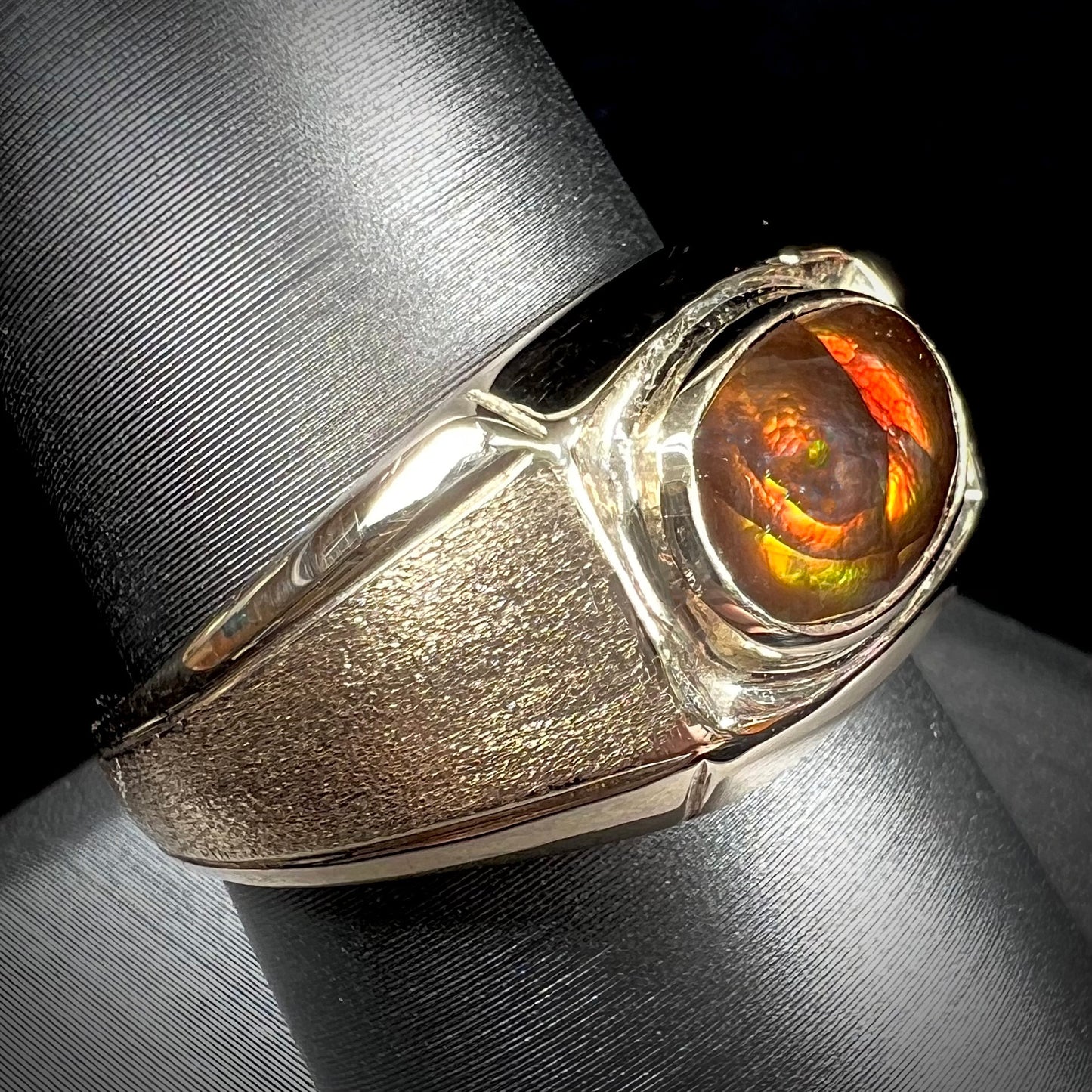 A yellow gold men's fire agate solitaire ring. The fire agate is red with green undertones.