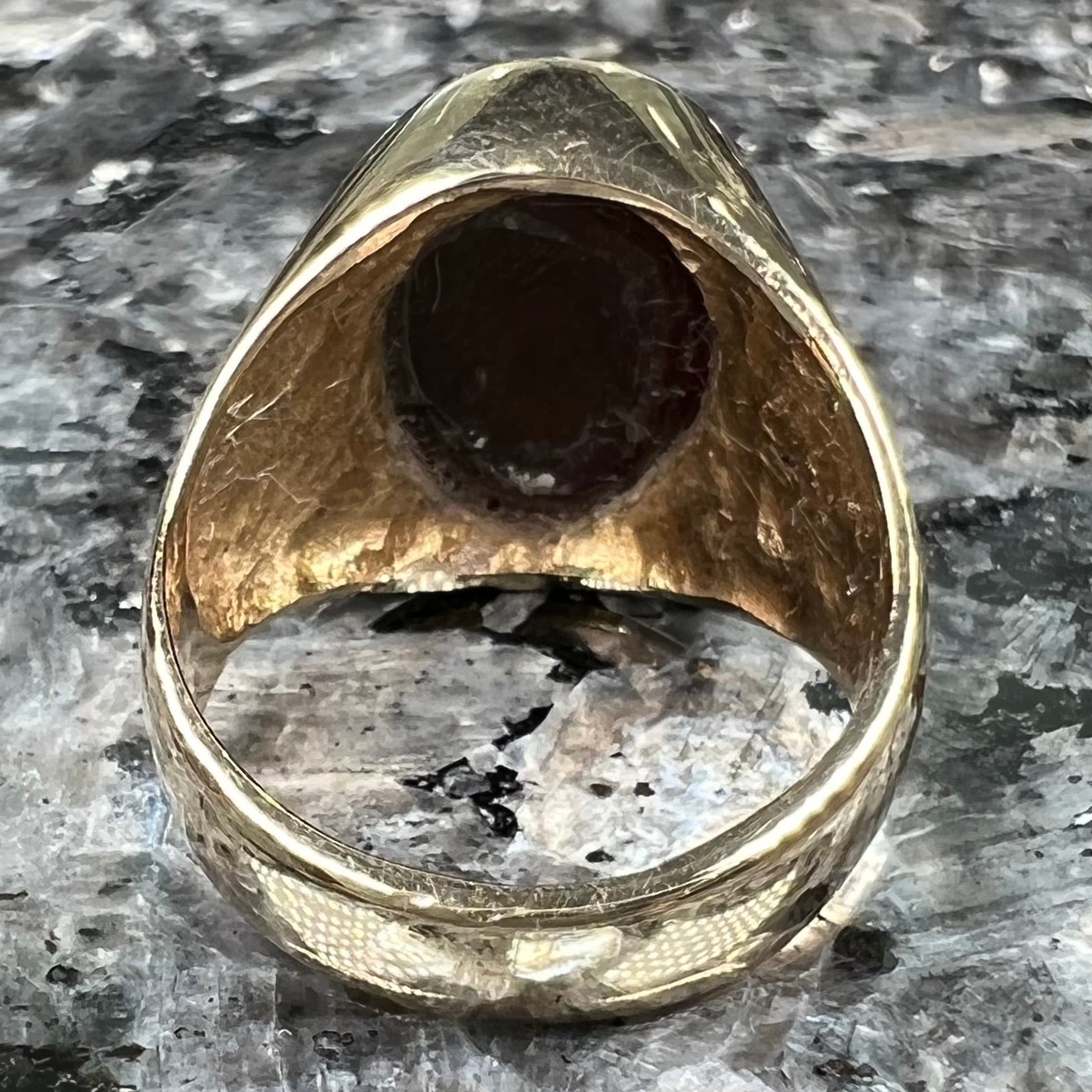A yellow gold solitaire fire agate men's ring. The fire agate is oval shape, and red and green in color.