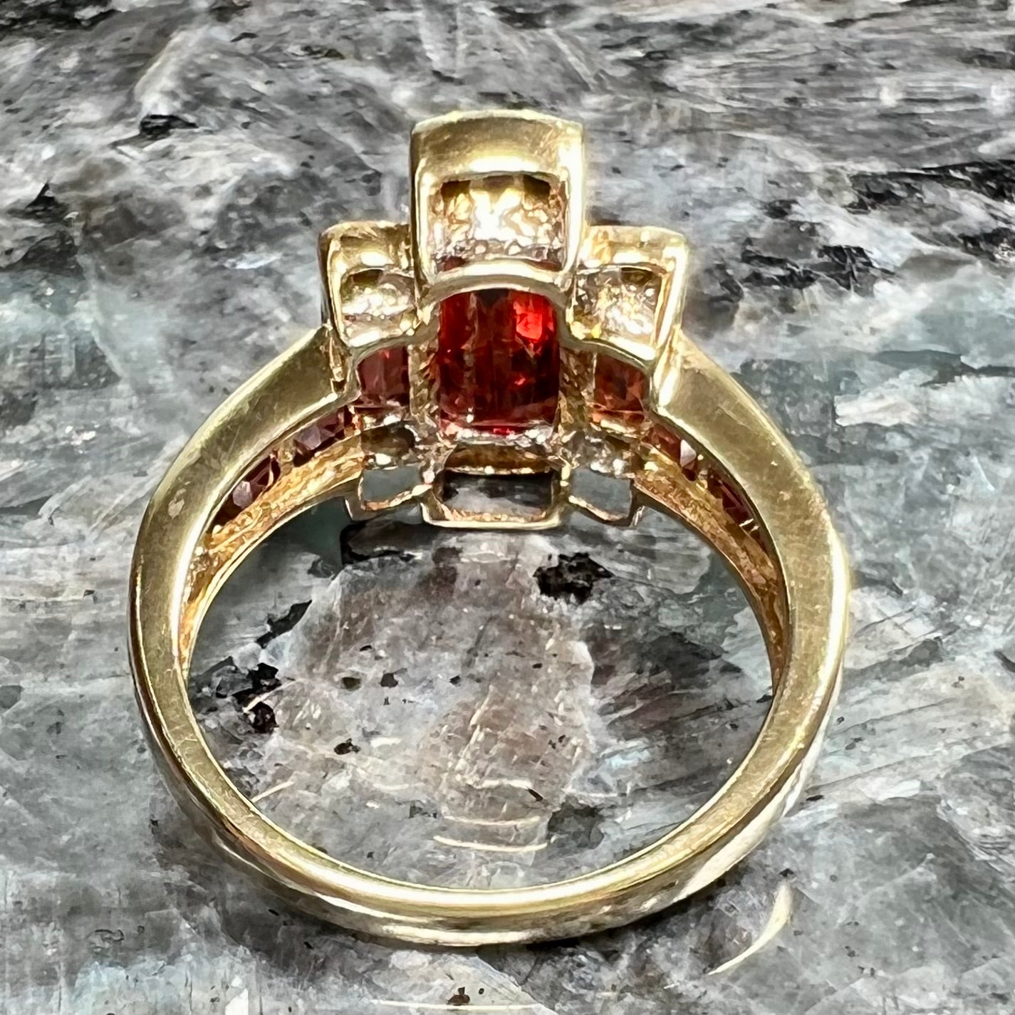 An Art Deco style emerald cut garnet and diamond ring cast in yellow gold.
