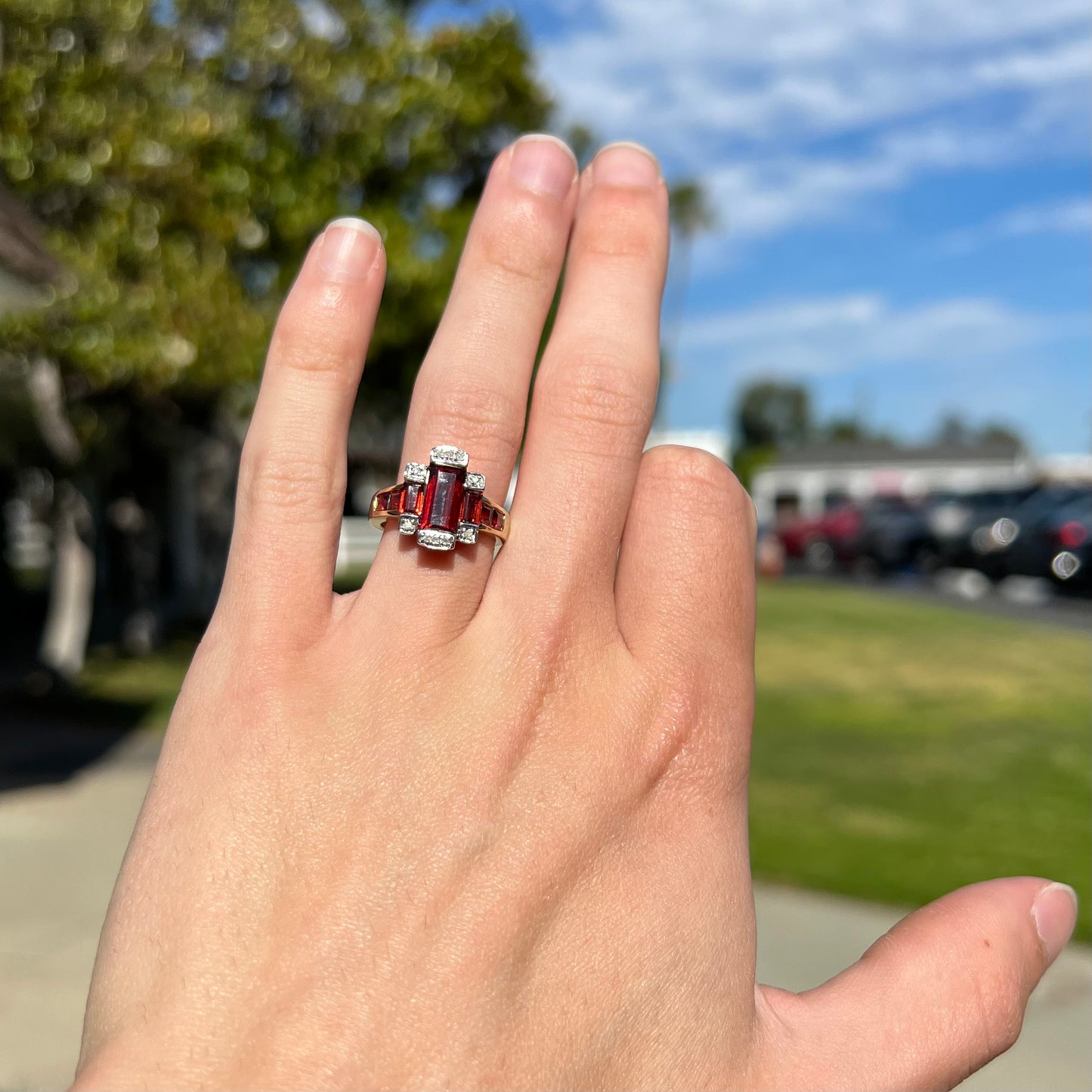 An Art Deco style emerald cut garnet and diamond ring cast in yellow gold.