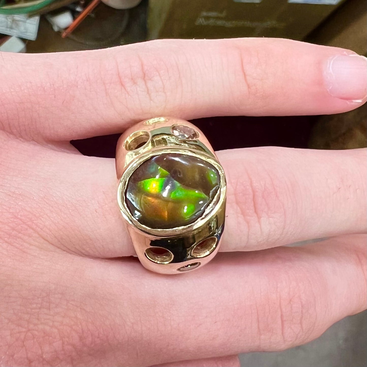 Men's rainbow fire agate ring set in yellow gold with champagne diamonds. The ring style has holes.