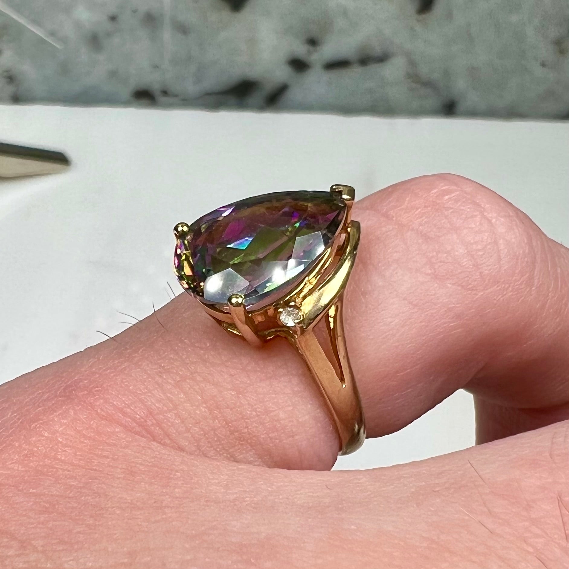 Pear shape green and pink mystic topaz set in a yellow gold ring with a single round diamond.