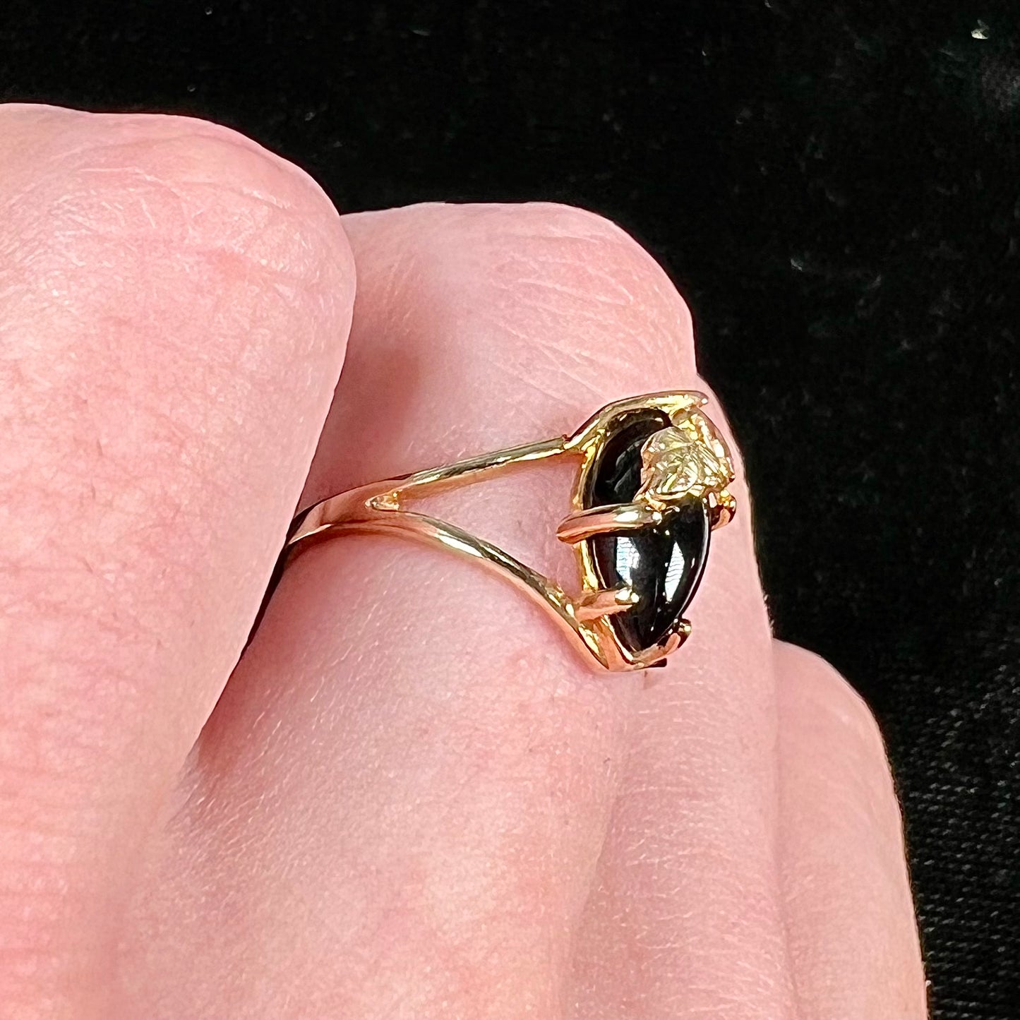 A split shank Black Hills gold ring set with a cabochon marquise cut black onyx.