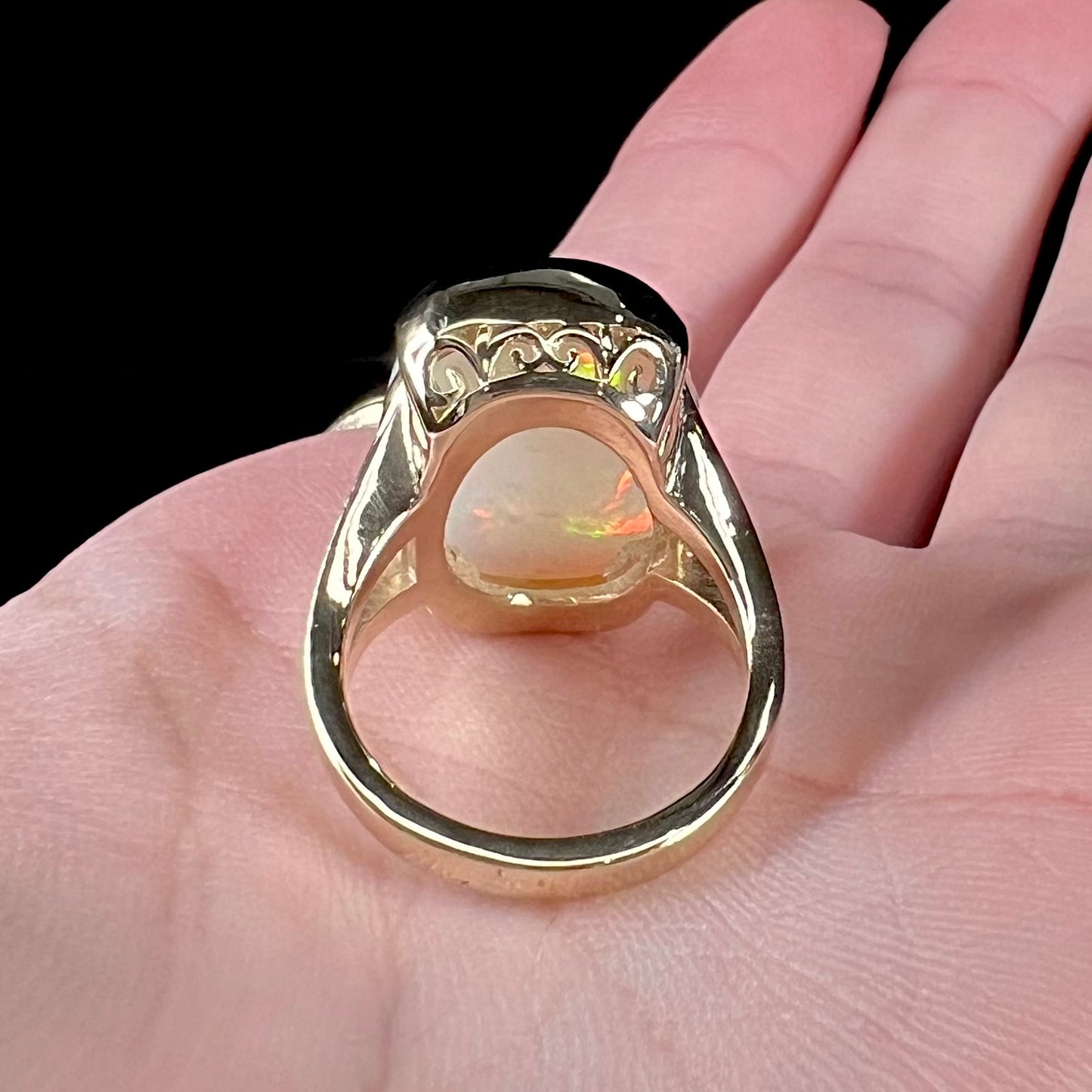 A ladies' yellow gold split shank ring half-bezel set with a barrel cabochon cut natural Ethiopian fire opal stone.