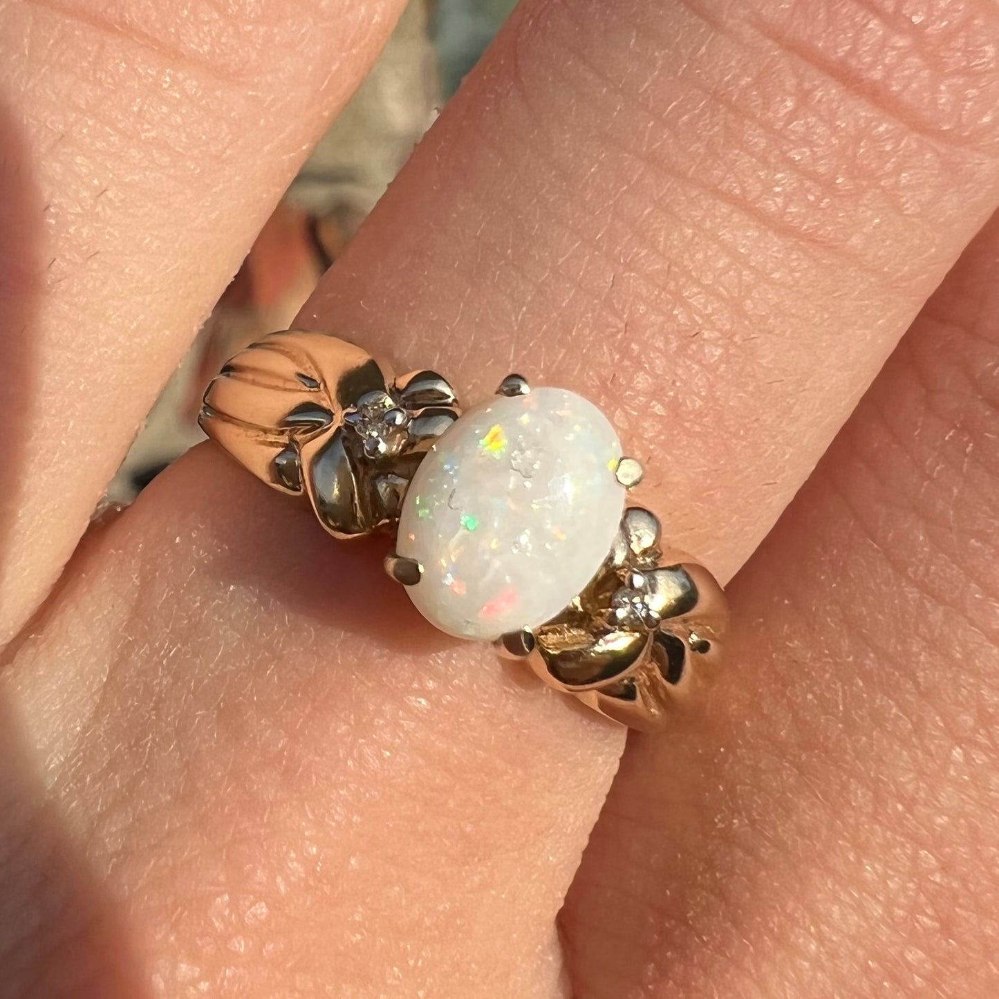 A ladies' yellow gold white crystal opal and diamond ring. The opal is prong set.