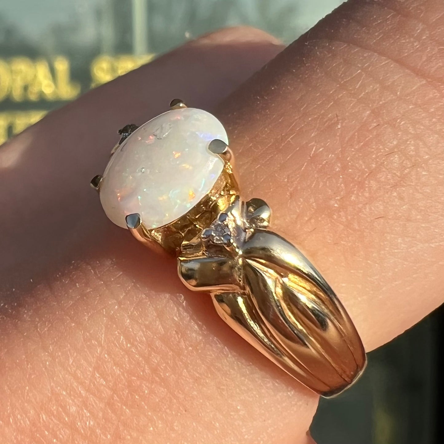 A ladies' yellow gold white crystal opal and diamond ring. The opal is prong set.