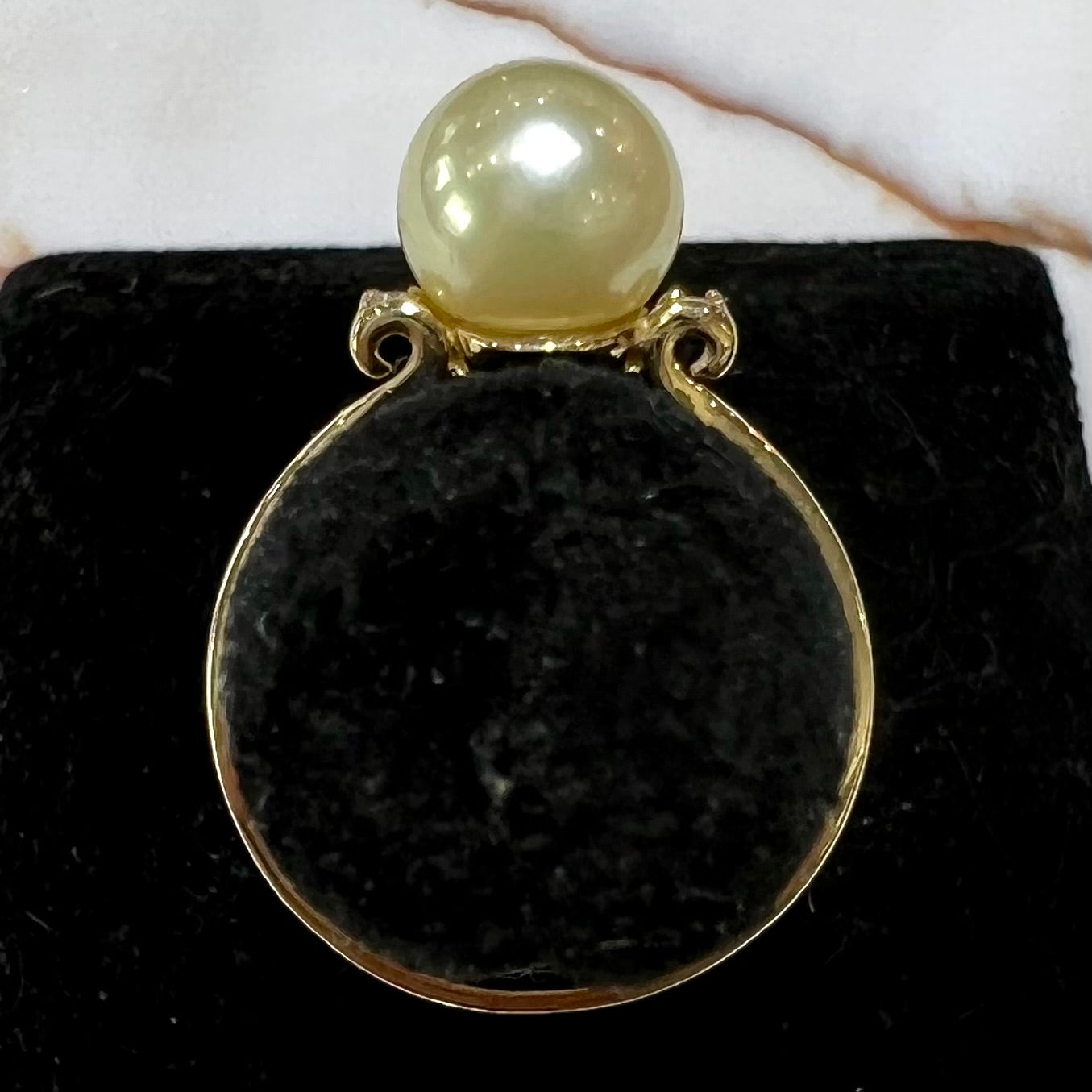 A simple, vintage, yellow gold pearl ring set with two side diamonds.