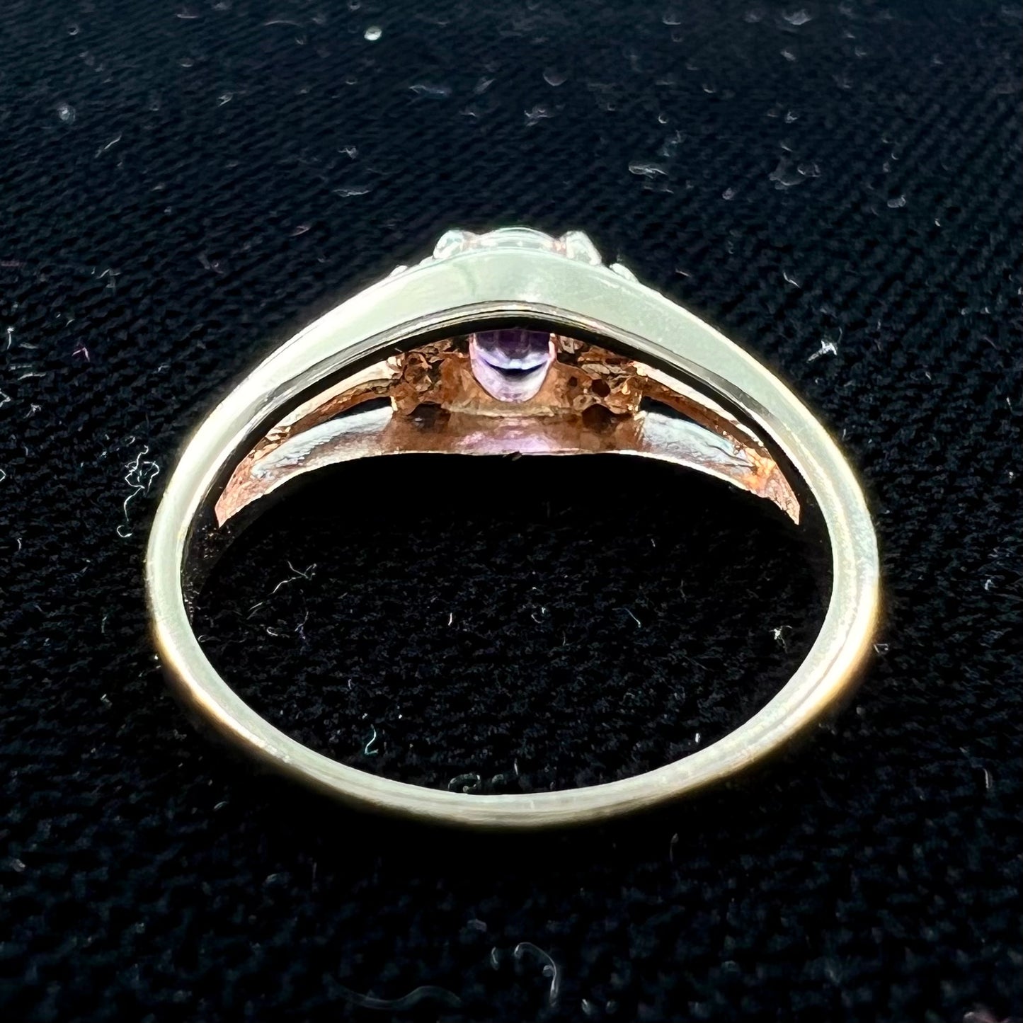 A ladies split shank gold ring set with an oval cut amethyst and round brilliant diamond accents.