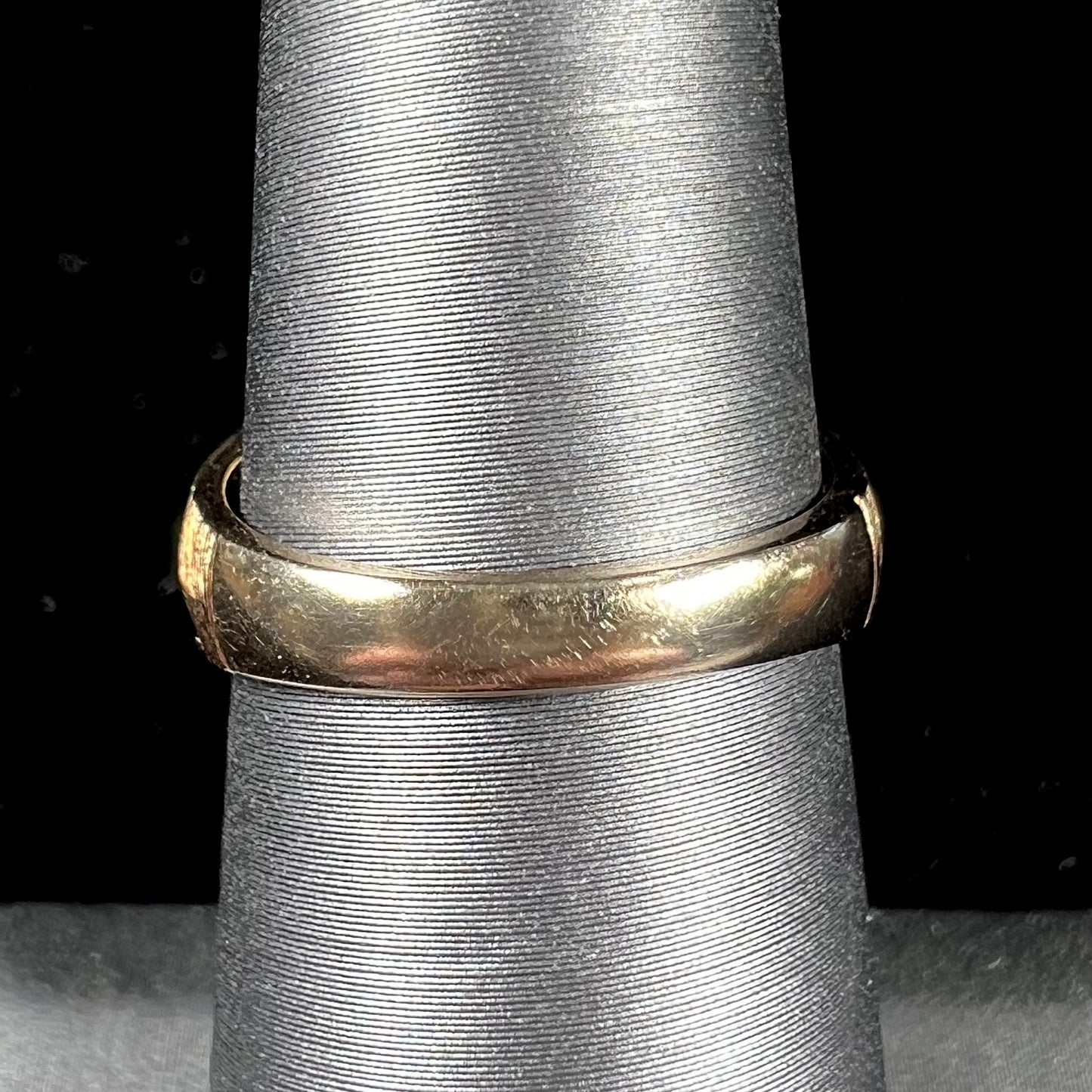 A textured yellow gold ring set with a marquise cabochon cut green jadeite stone.