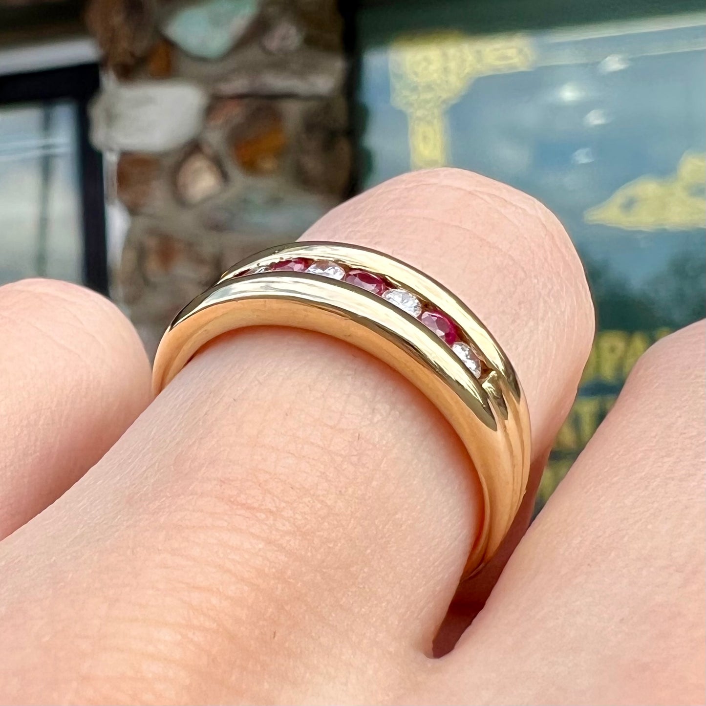 An 18kt yellow gold band channel set with round cut rubies and diamonds.