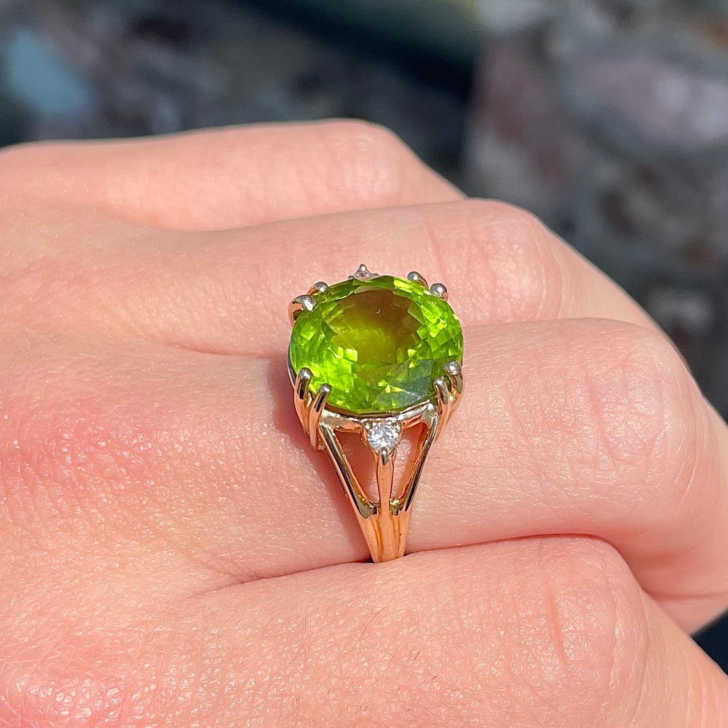 A ladies' round brilliant cut peridot statement ring set with two round diamond accents in yellow gold.