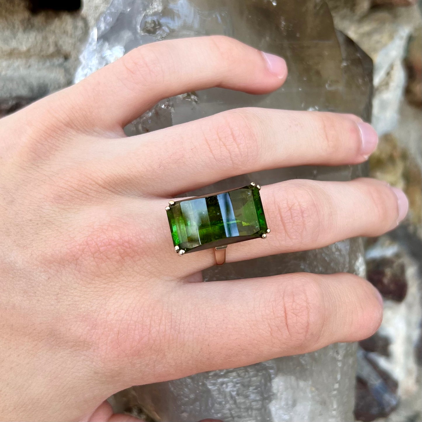 A faceted step-cut dark green tourmaline basket set solitaire ring cast in yellow gold.