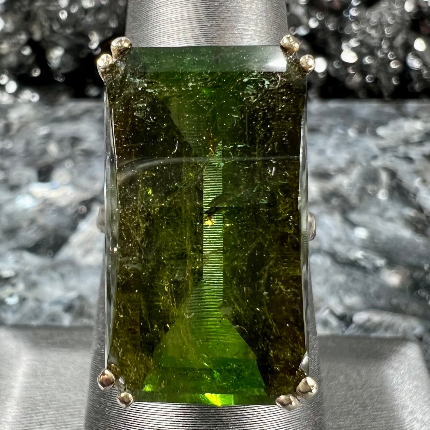 A faceted step-cut dark green tourmaline basket set solitaire ring cast in yellow gold.