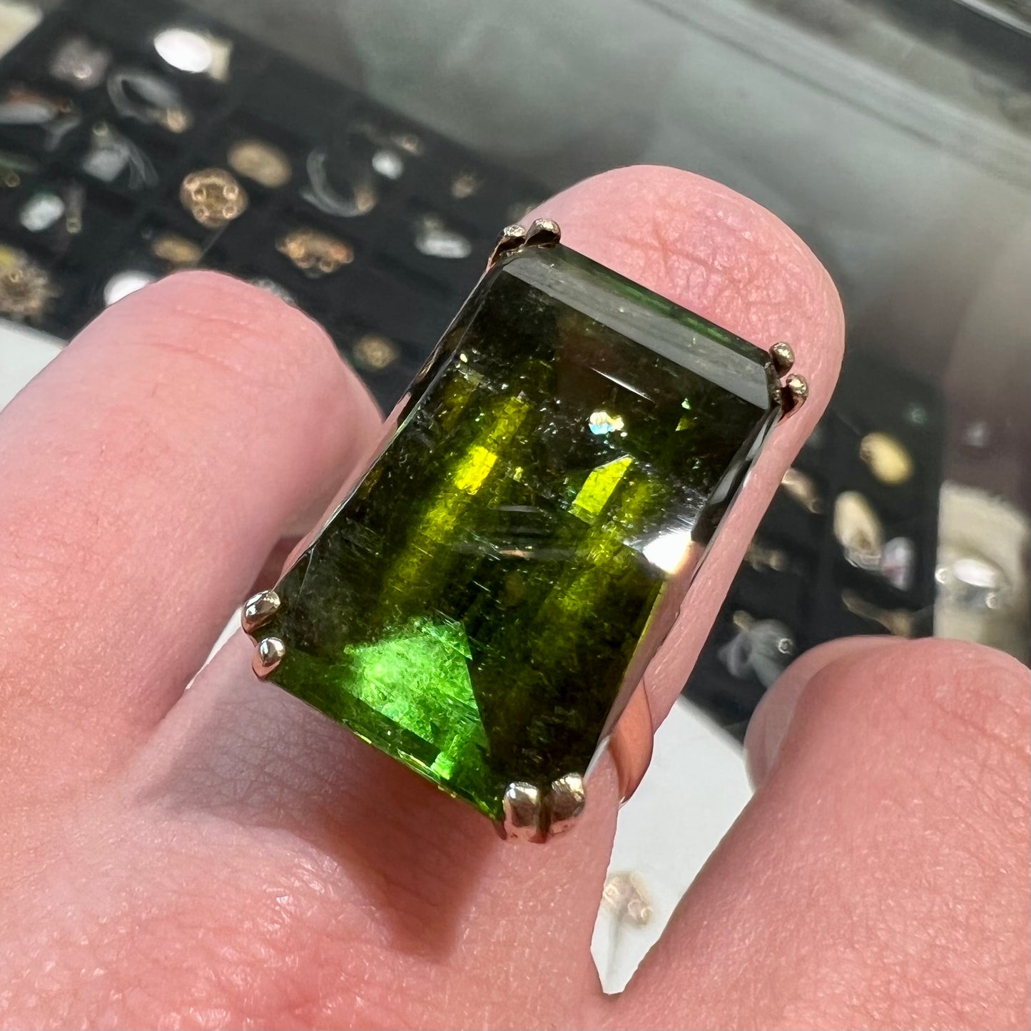 A faceted step-cut dark green tourmaline basket set solitaire ring cast in yellow gold.