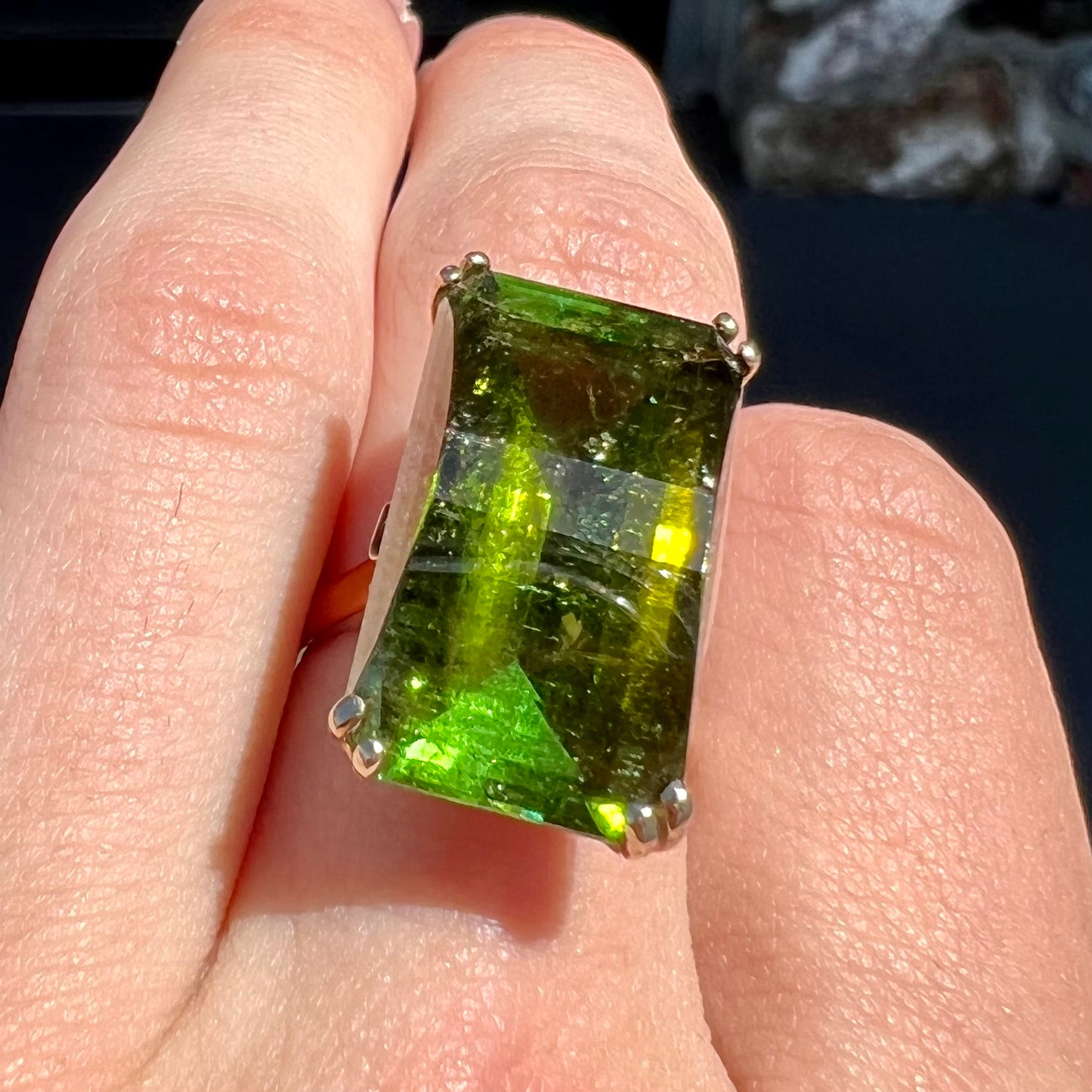 A faceted step-cut dark green tourmaline basket set solitaire ring cast in yellow gold.