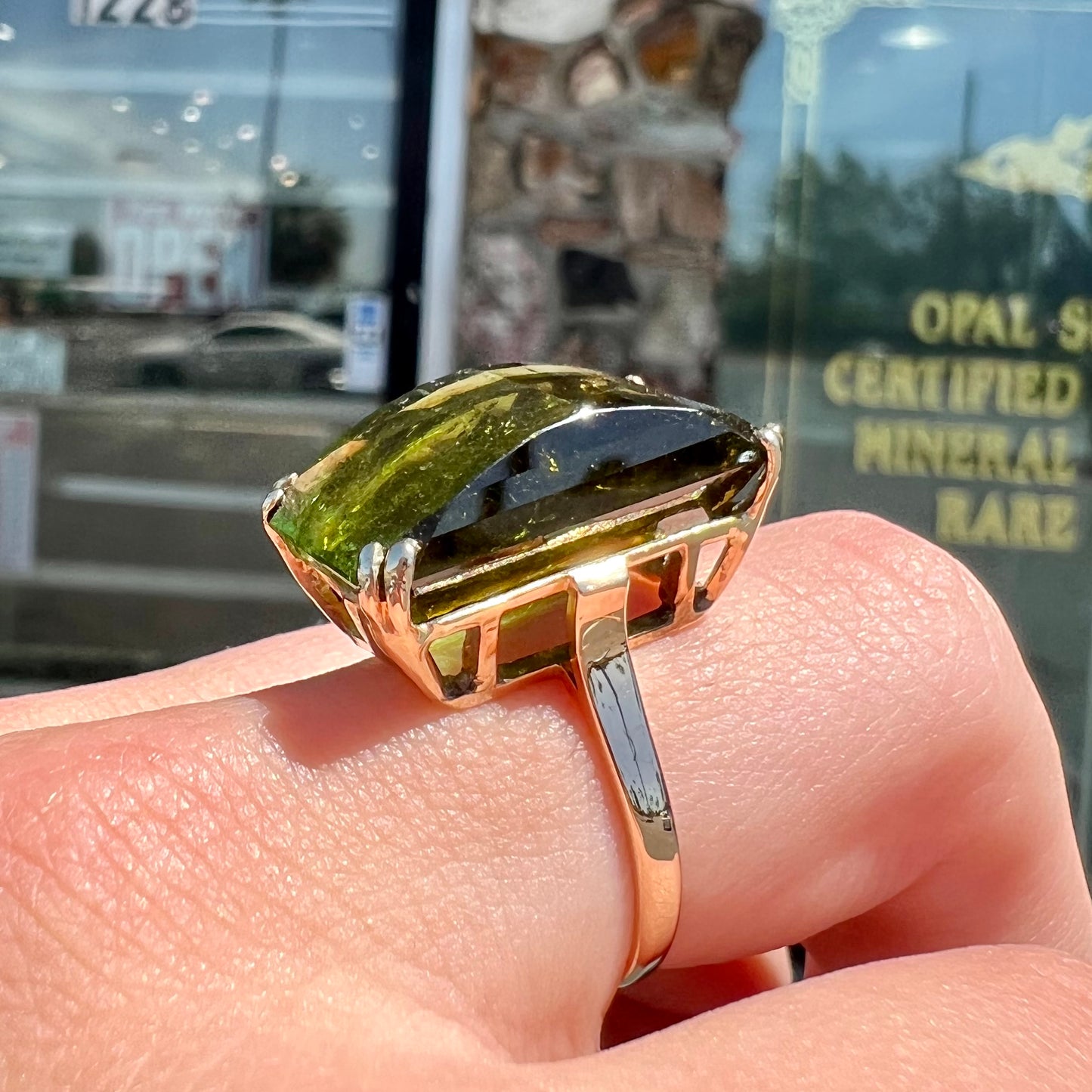 A faceted step-cut dark green tourmaline basket set solitaire ring cast in yellow gold.