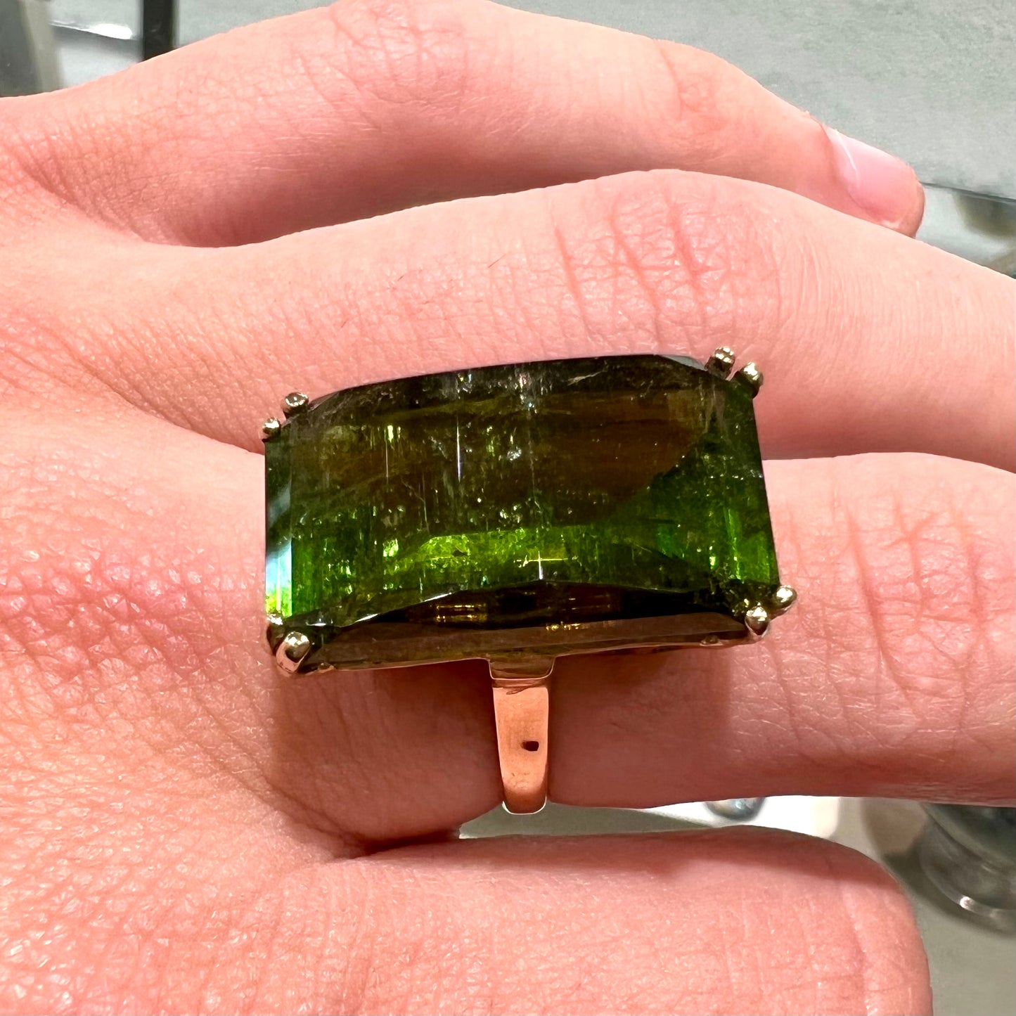 A faceted step-cut dark green tourmaline basket set solitaire ring cast in yellow gold.