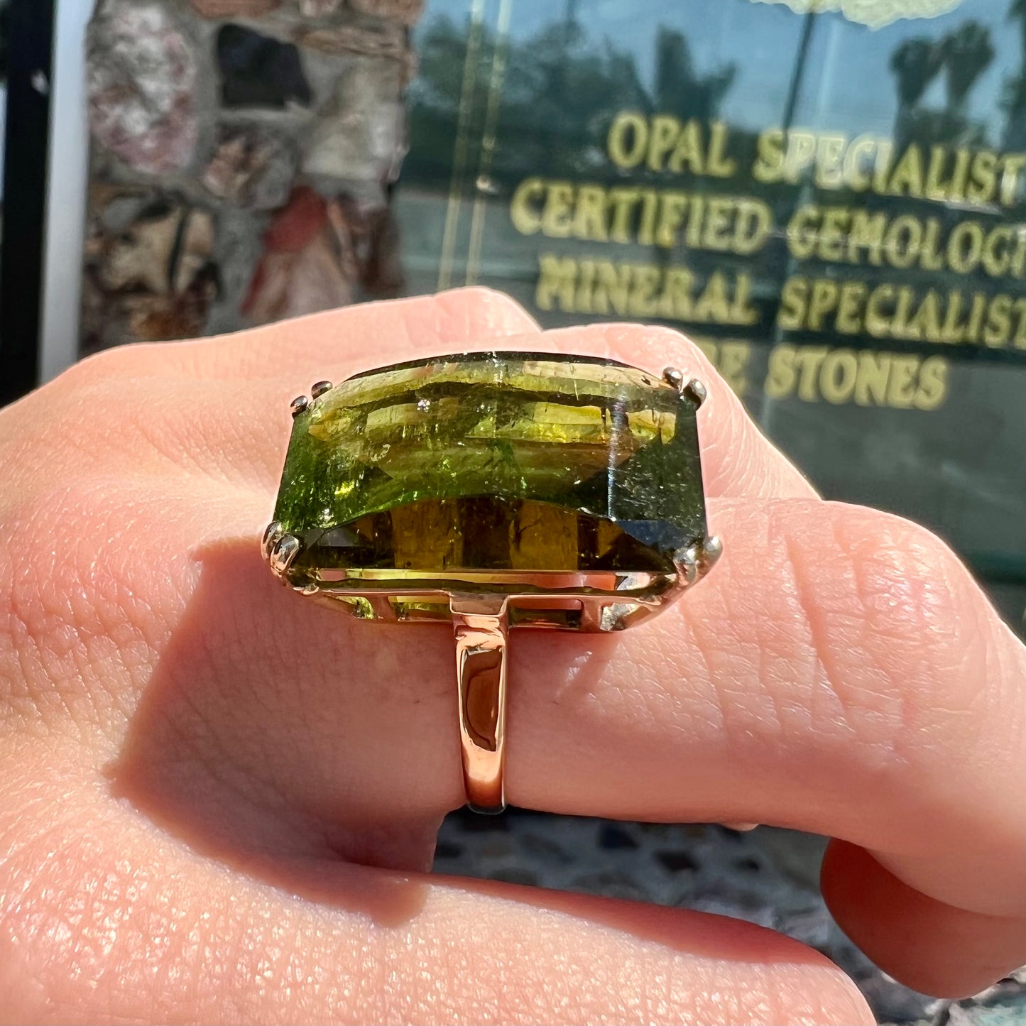 A faceted step-cut dark green tourmaline basket set solitaire ring cast in yellow gold.
