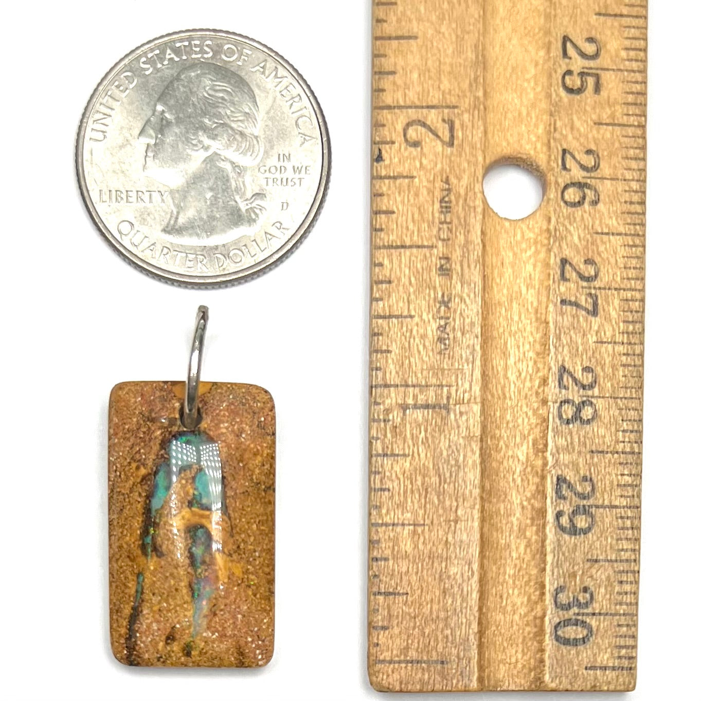 A drilled boulder opal stone with a sterling silver ring through the hole to be worn as a pendant. The pattern resembles a hamsa hand.