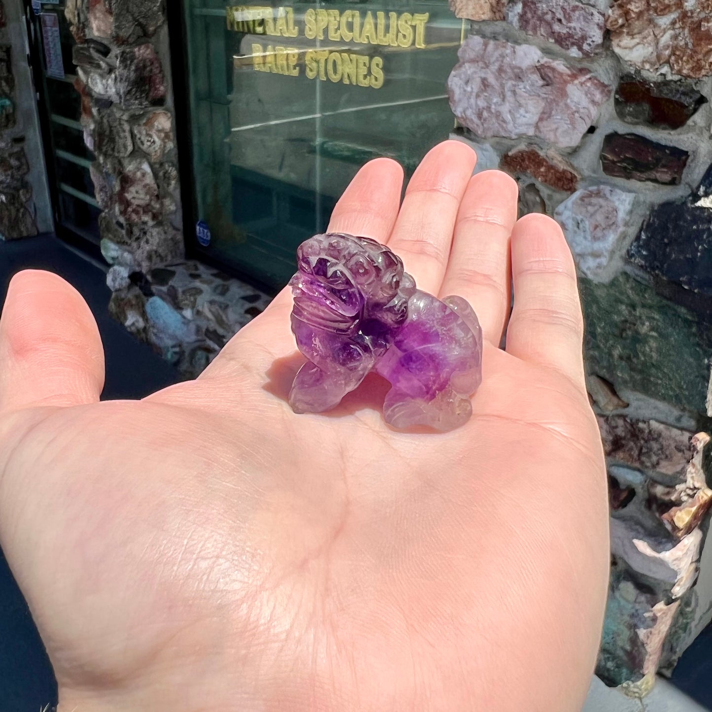 A stone foo dog carving carved from a purple Brazilian amethyst crystal.