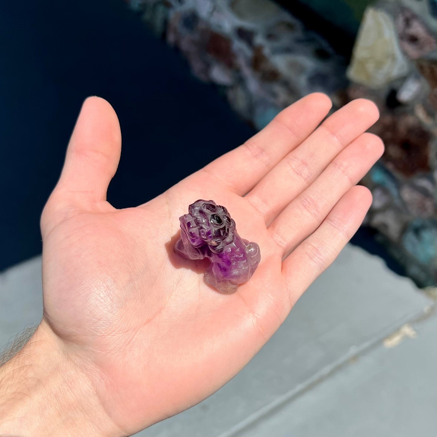 A stone foo dog carving carved from a purple Brazilian amethyst crystal.