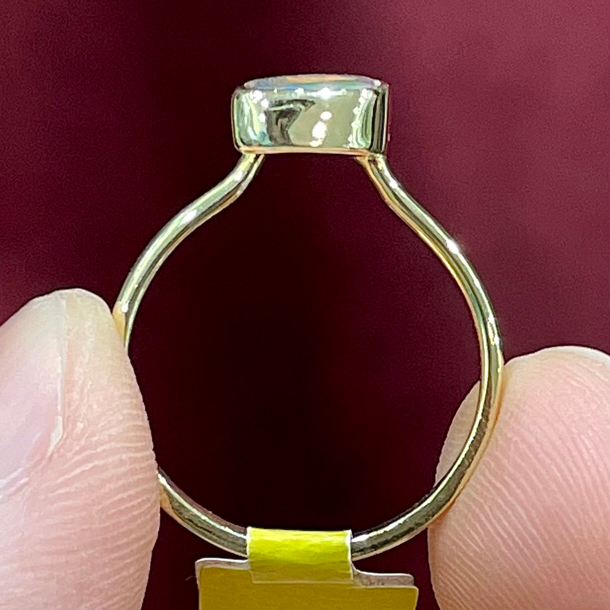A handmade yellow gold solitaire ring bezel set with a Lightning Ridge red-on-black harlequin opal.