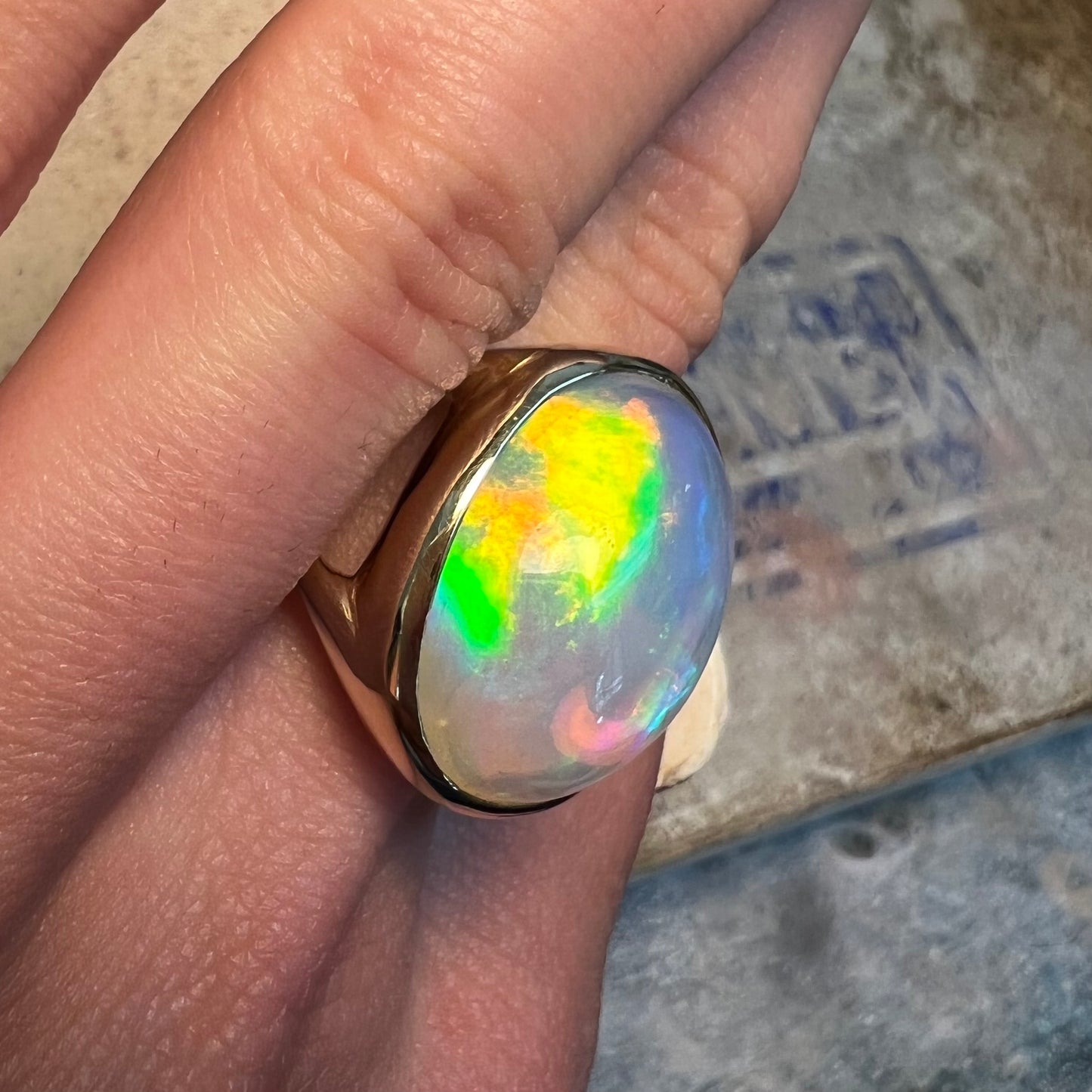A gold split shank solitaire ring set with an oval cabochon cut 16.83 carat Ethiopian jelly fire opal.