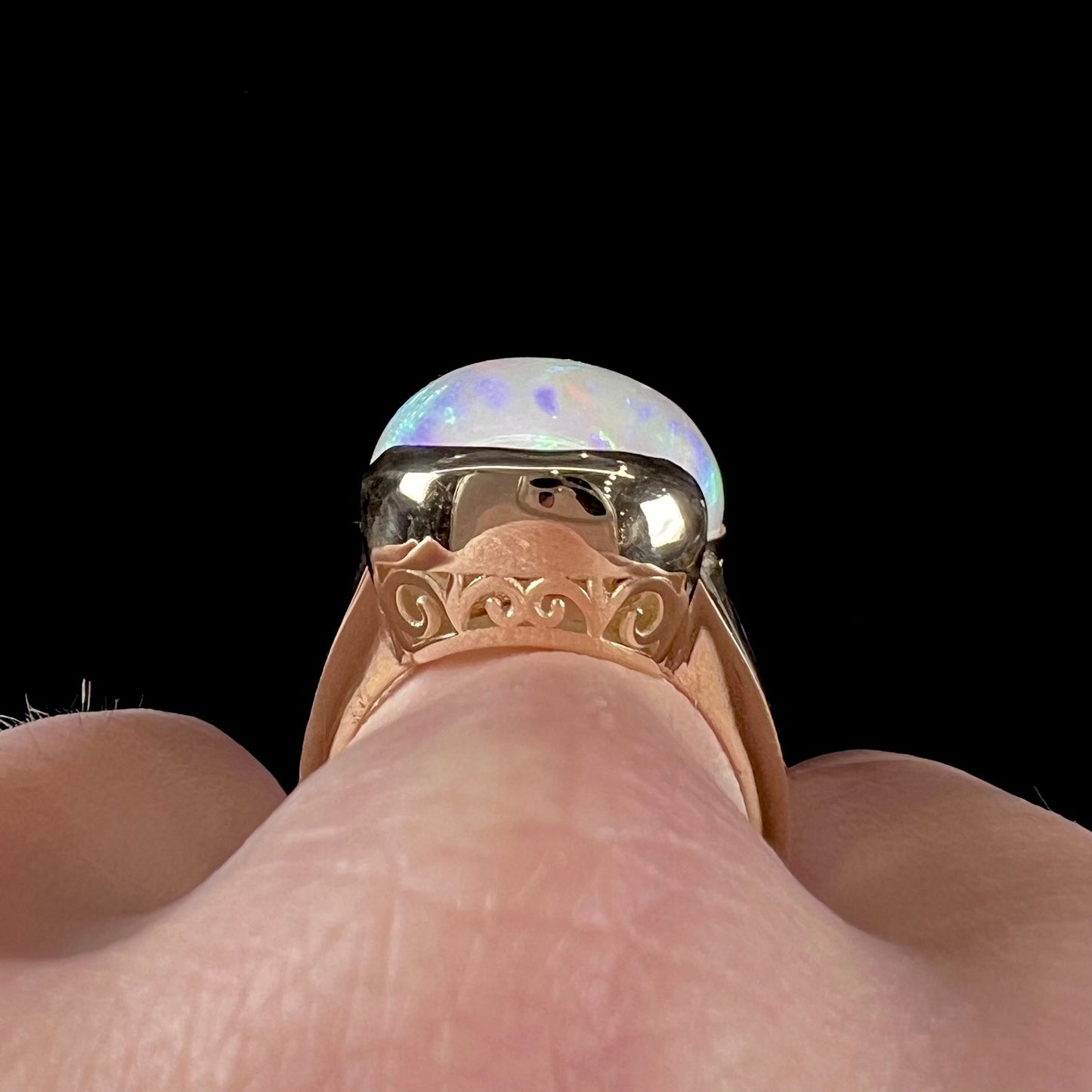 A ladies' yellow gold split shank ring half-bezel set with a barrel cabochon cut natural Ethiopian fire opal stone.