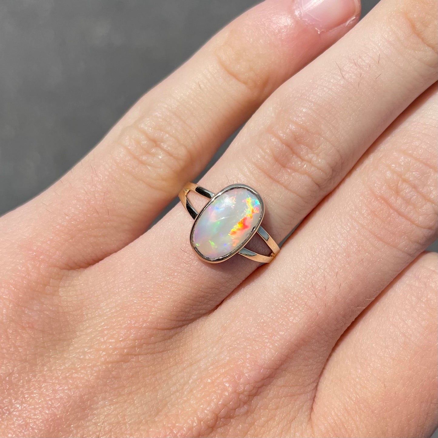 A handmade split shank white opal solitaire ring in yellow gold.