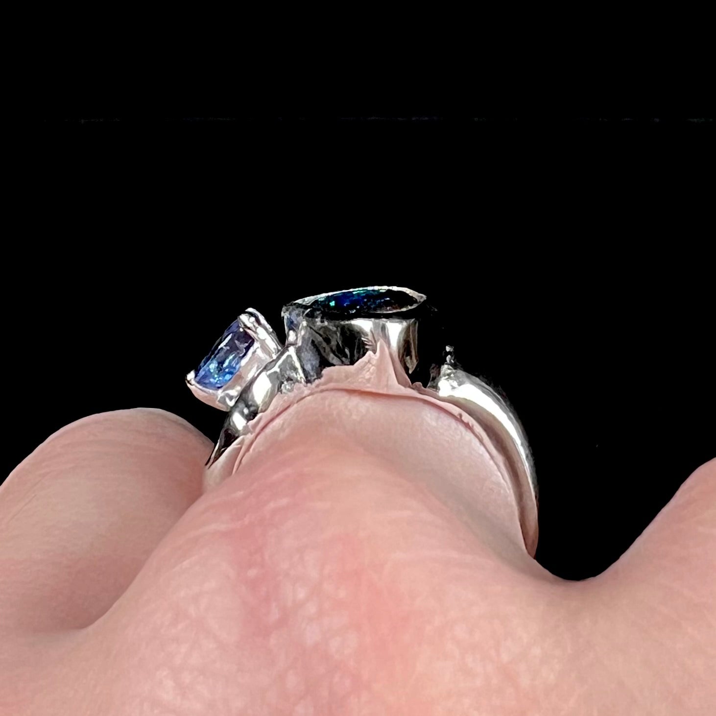 A ladies' white gold ring set with Australian black boulder opal and pear shape blue sapphire.