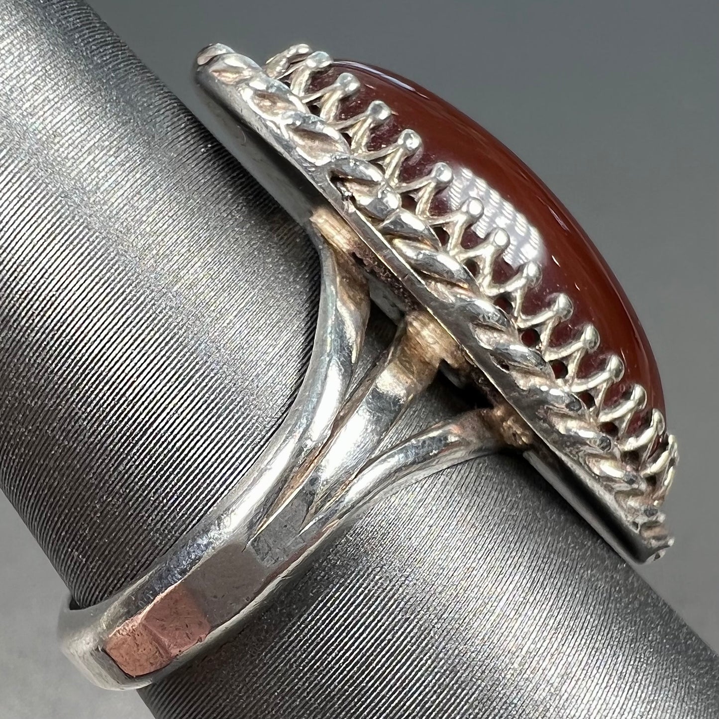 A split shank silver ring set with a brown sard stone in a rope bezel with small prongs.