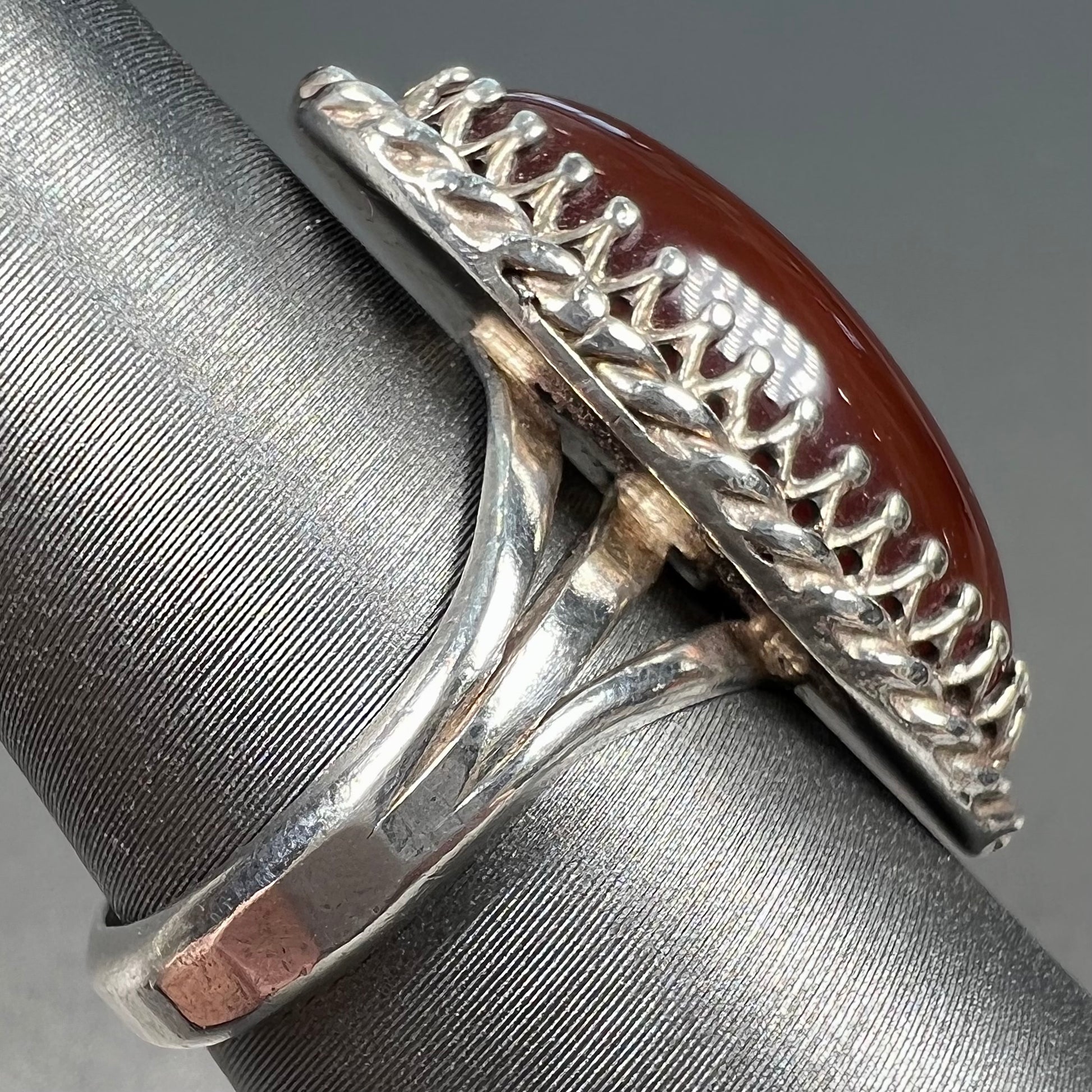 A split shank silver ring set with a brown sard stone in a rope bezel with small prongs.