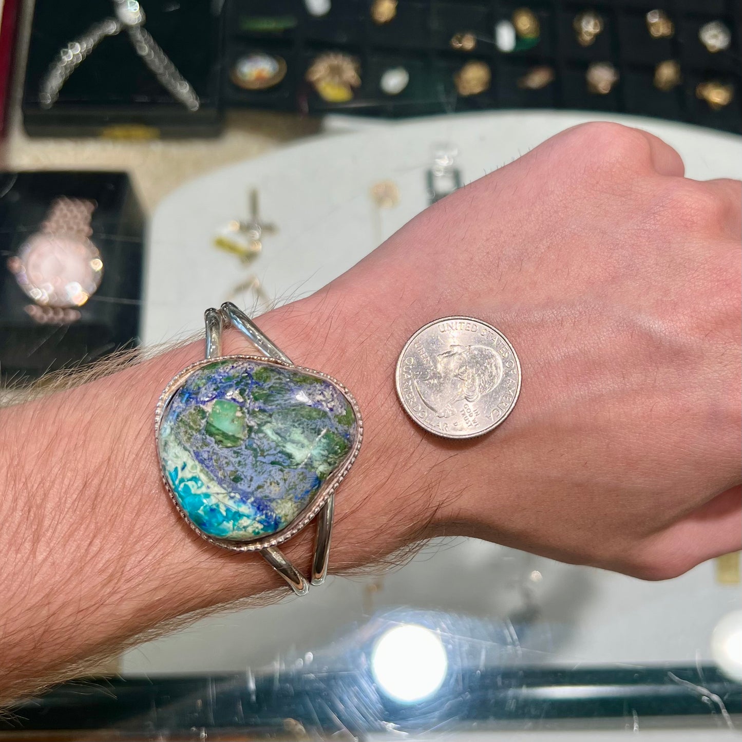 A handmade sterling silver cuff bracelet set with a single stone formed from variscite, chrysocolla, and azurite.