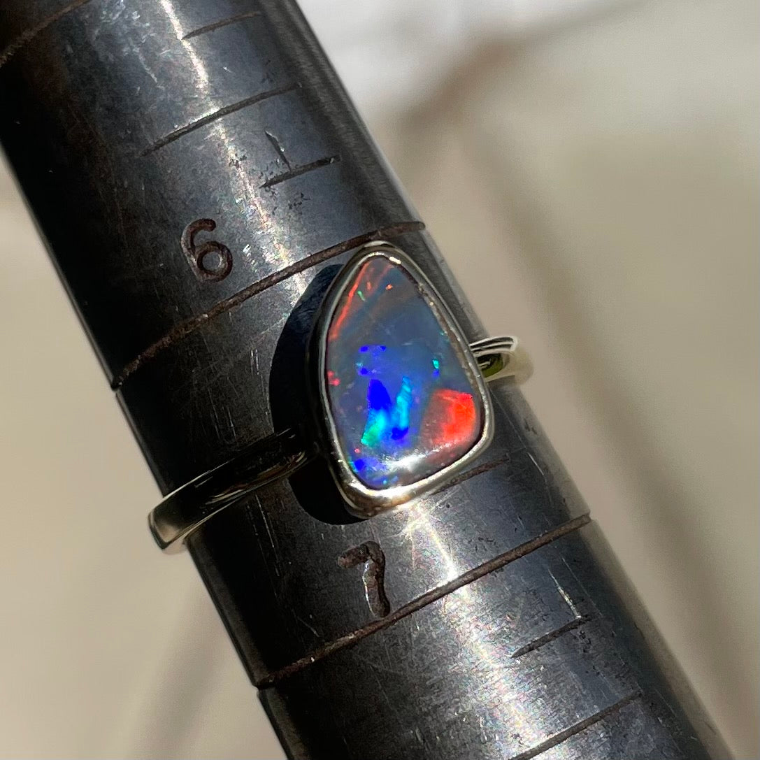 A handmade yellow gold solitaire ring bezel set with a Lightning Ridge red-on-black harlequin opal.