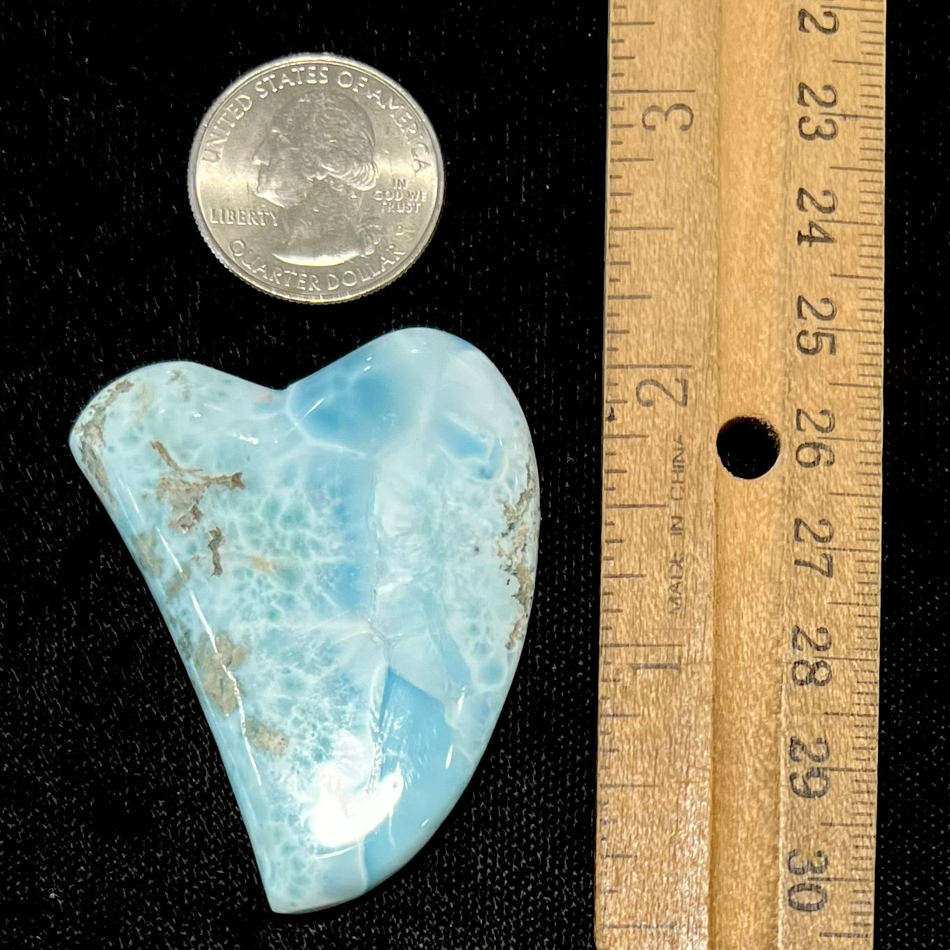 A loose larimar stone that has been hand-carved in the shape of a freeform heart.