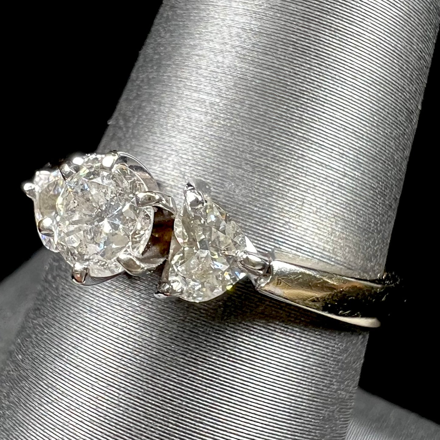A ladies' three stone diamond ring. The center diamond is a round brilliant cut, and the two accents are heart shaped diamonds.