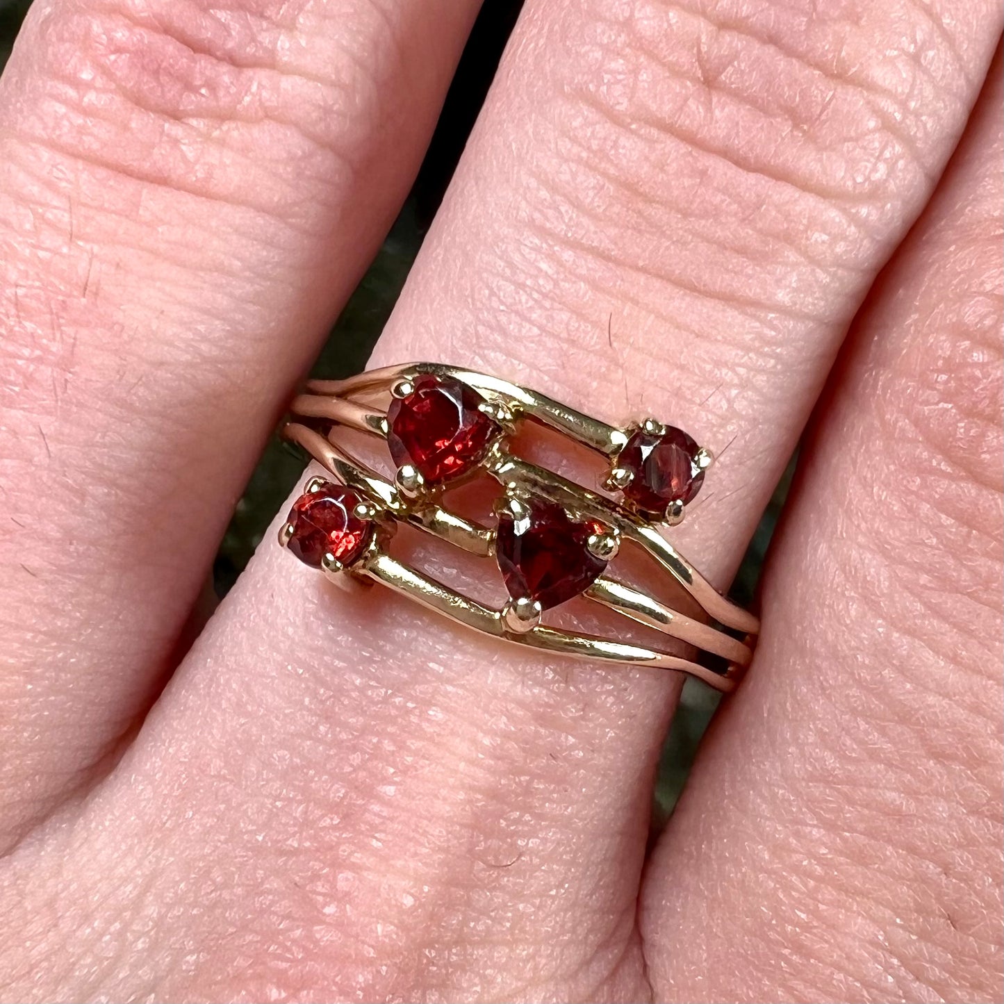 A yellow gold multishank ring set with two heart shape and two round cut red garnets.
