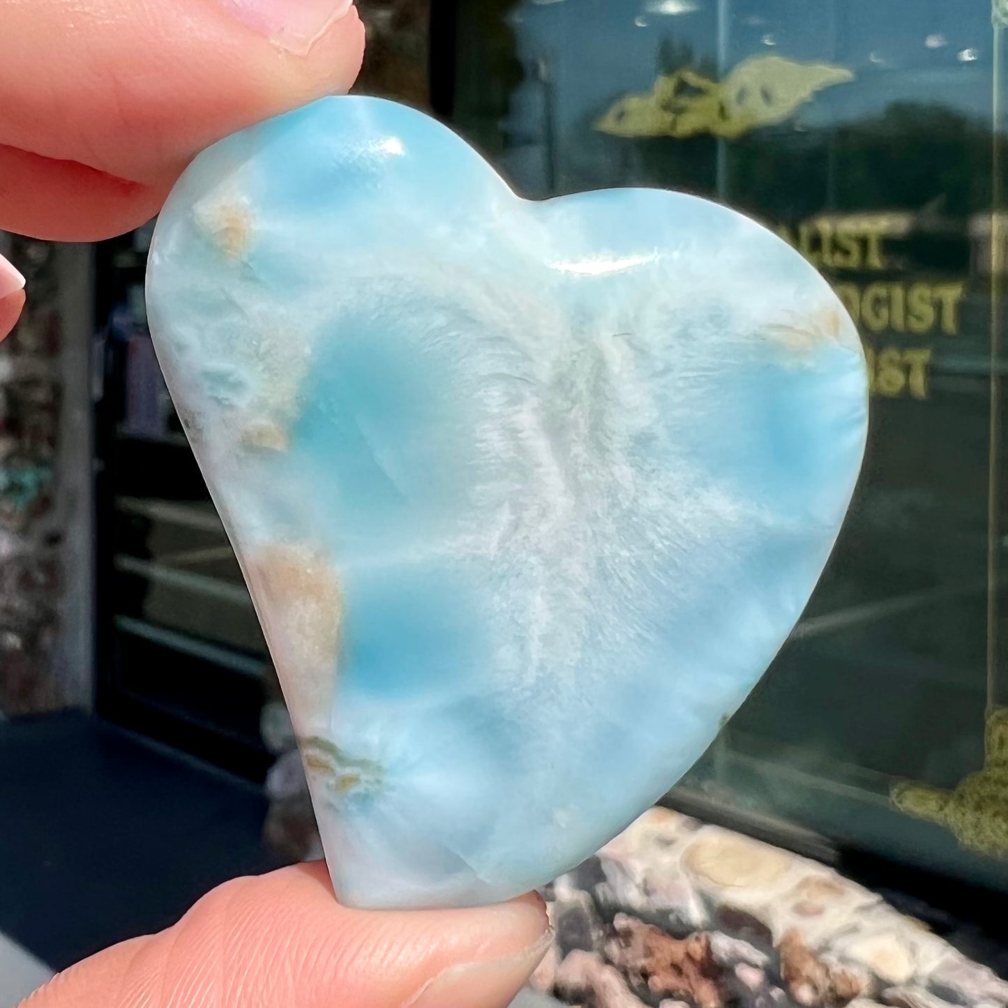 A loose, carved, heart shaped larimar stone. Predominant colors are blue and white.