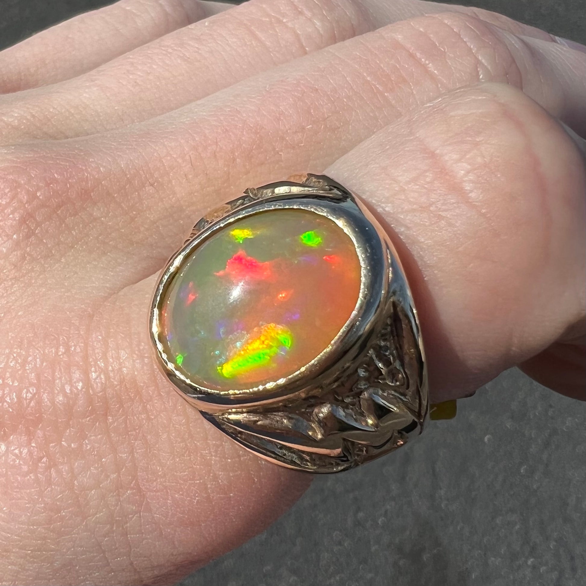 A solid yellow gold solitaire men's fire opal ring.  The stone is an orange oval cabochon cut.