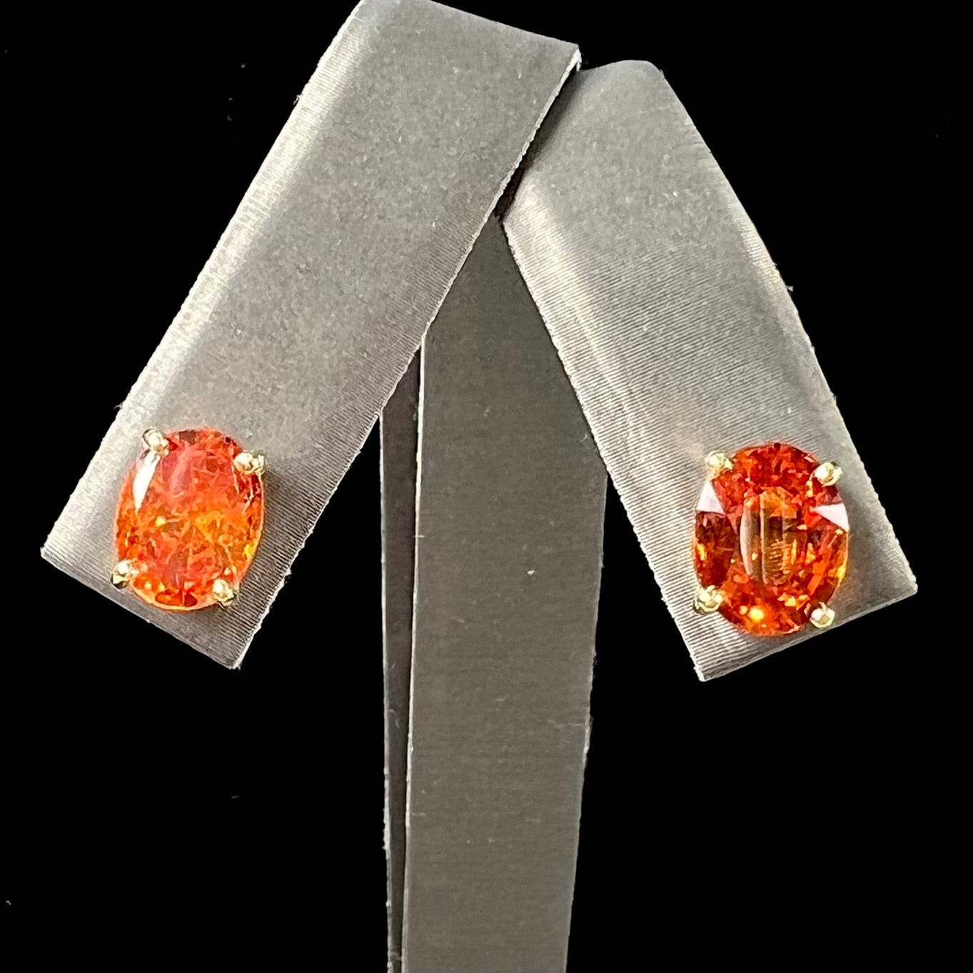 A pair of yellow gold orange hessonite garnet stud earrings. The garnets are faceted oval cut.