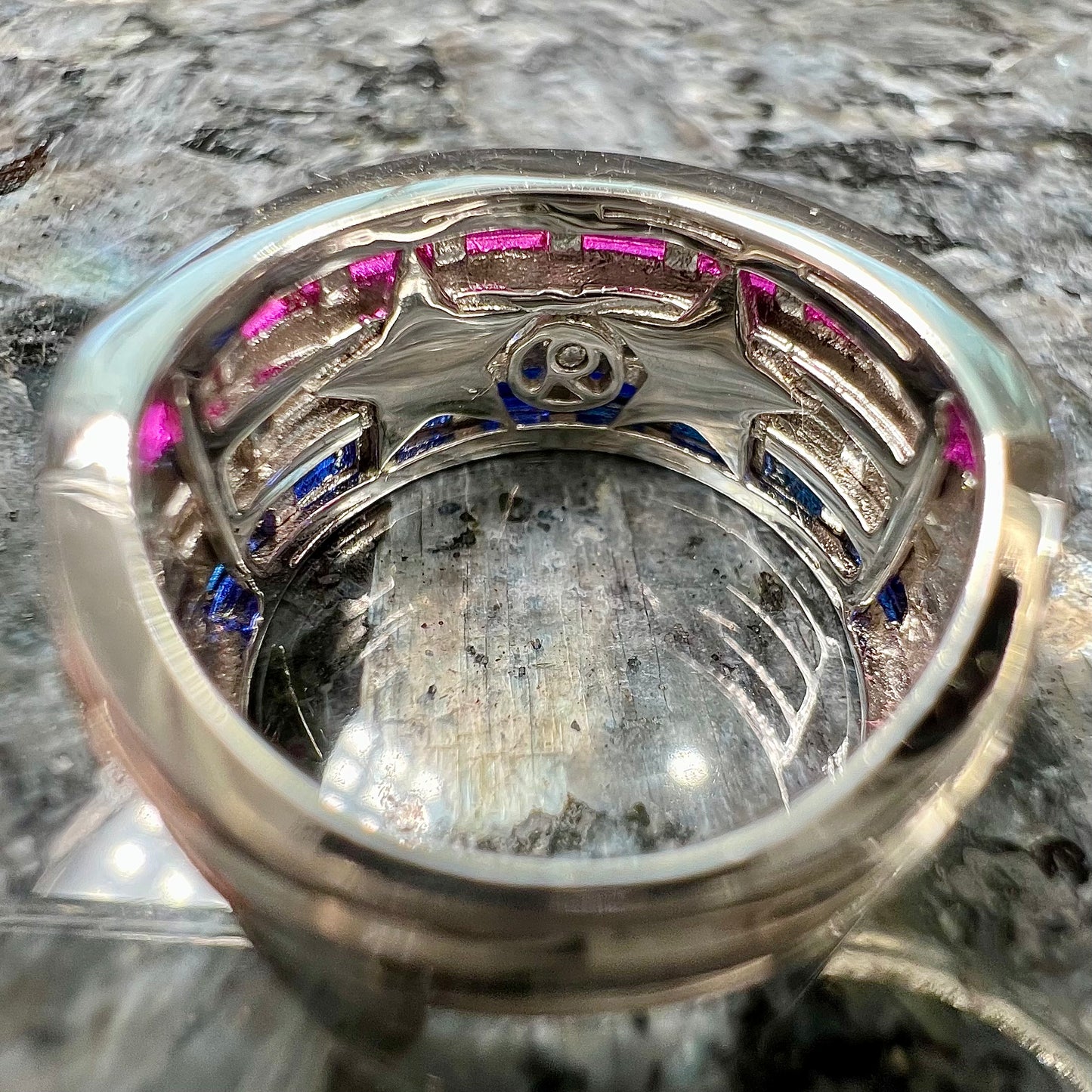 A silver ring set with red, white, and blue baguette cut stones. The gallery features two stars.