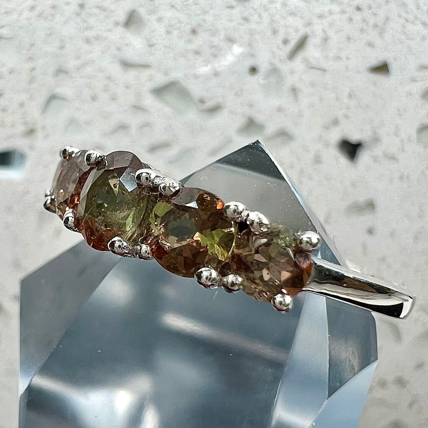 A sterling silver stackable ring set with five faceted oval and round andalusite stones.