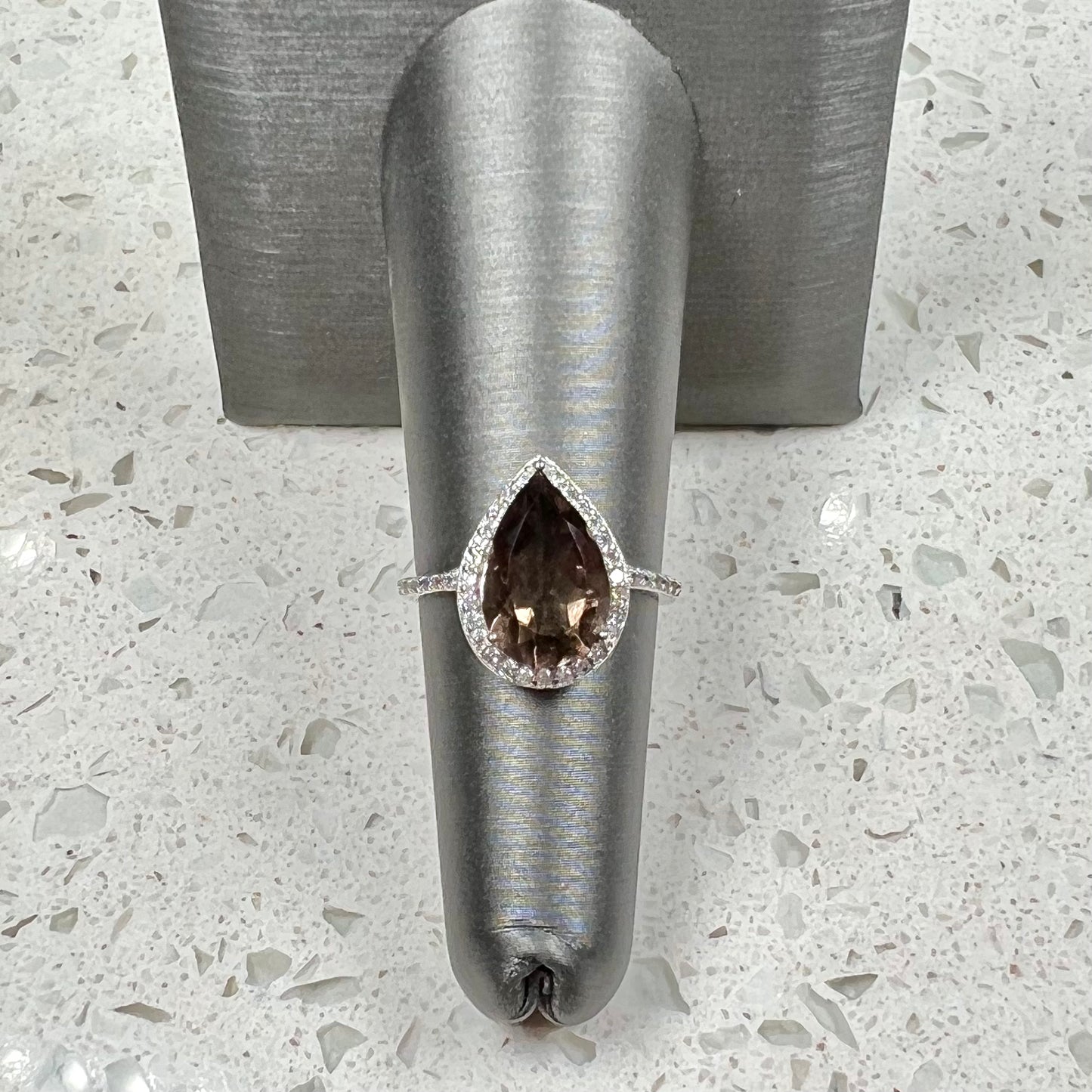 A pear shape smoky quartz set in a sterling silver and CZ halo ring.