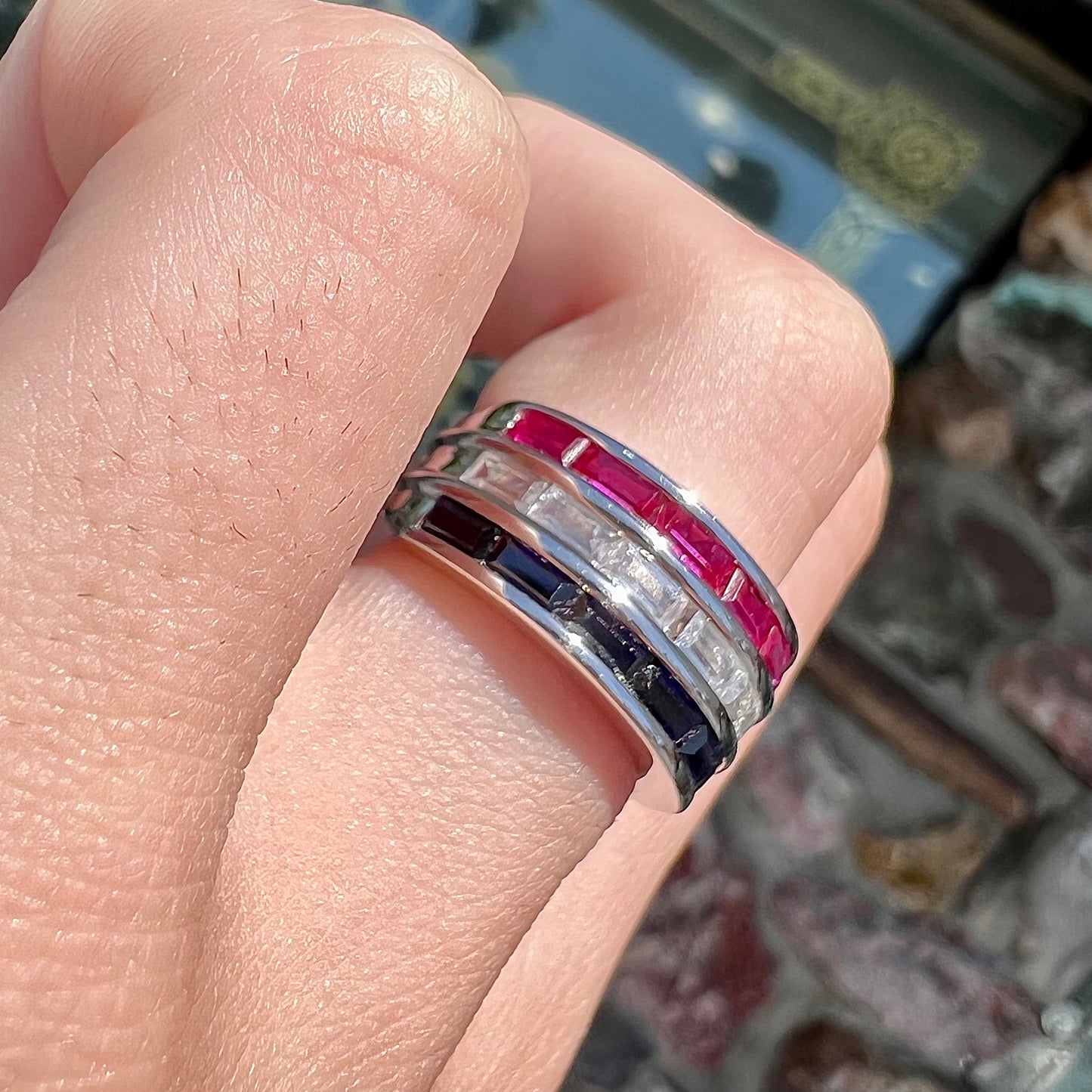 A silver ring set with red, white, and blue baguette cut stones. The gallery features two stars.